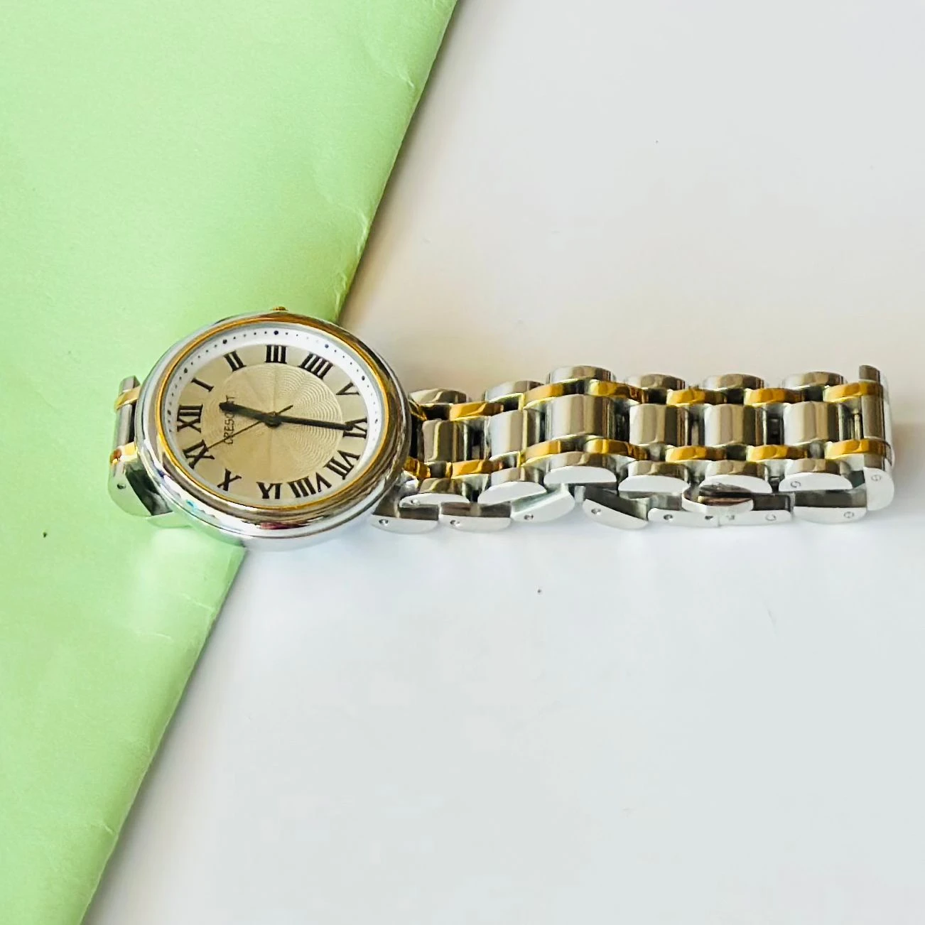 Crescent analog watch with a rectangular case and a two-tone (silver and gold) metal bracelet.