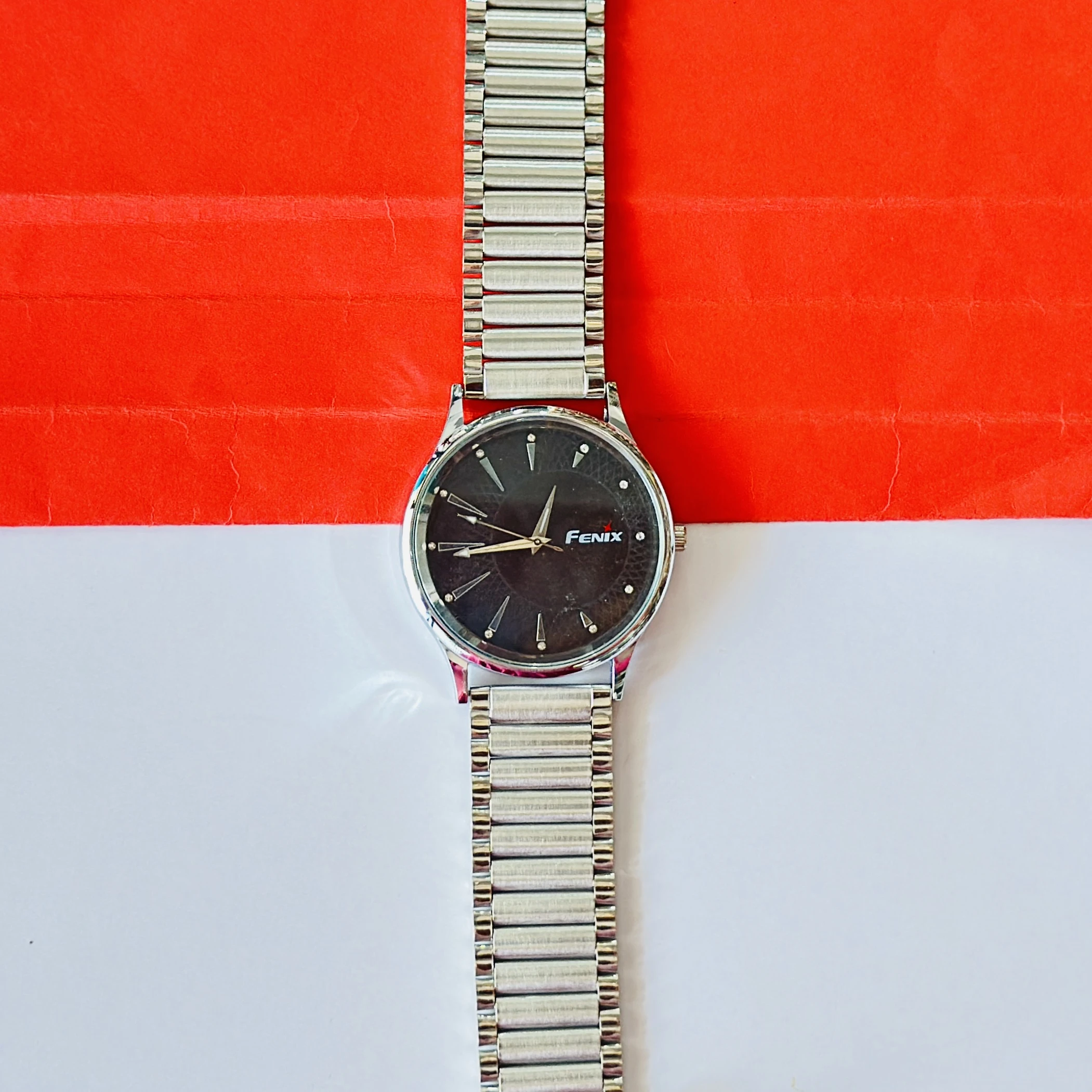 Analogue timepiece with a black dial and a silver stainless steel strap.
