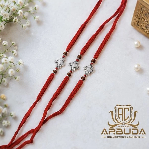 Hindu Rakhis featuring a silver-toned Ganesha pendant on a red thread.