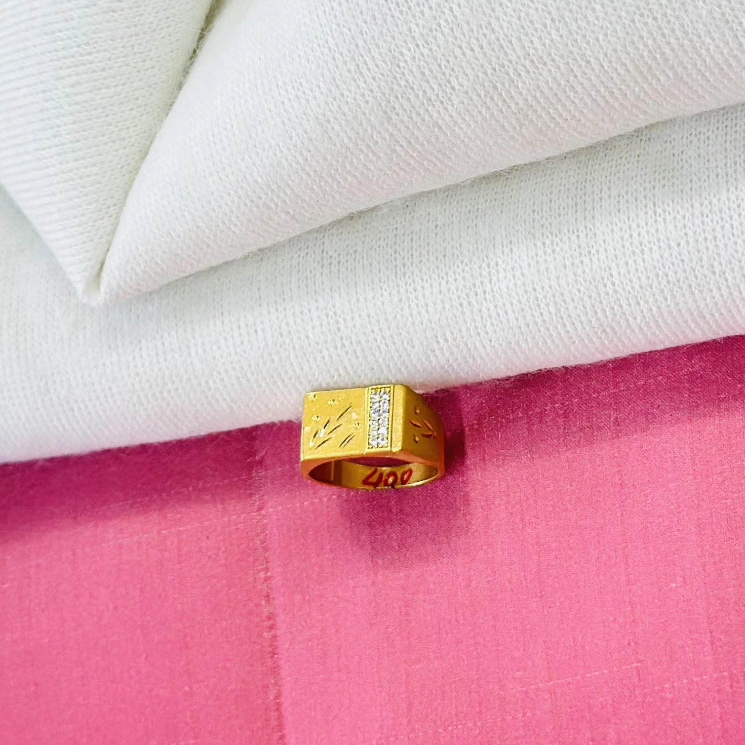 An engraved gold-toned men's ring with small white stones.