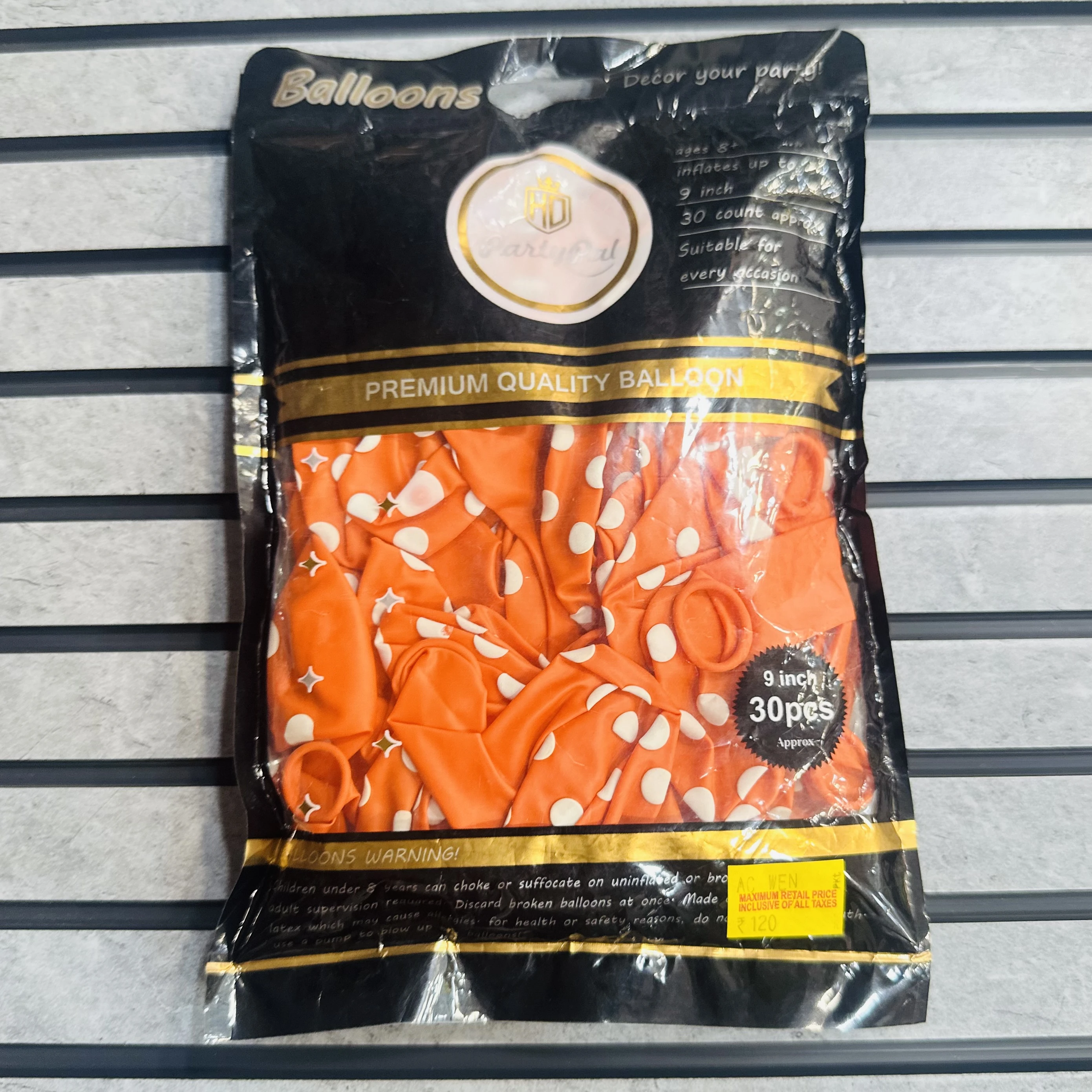 package of orange party balloons with white polka dots.