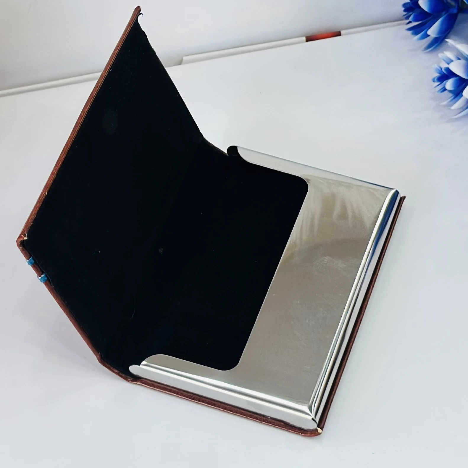 brown leather business card holder with blue metal accents.