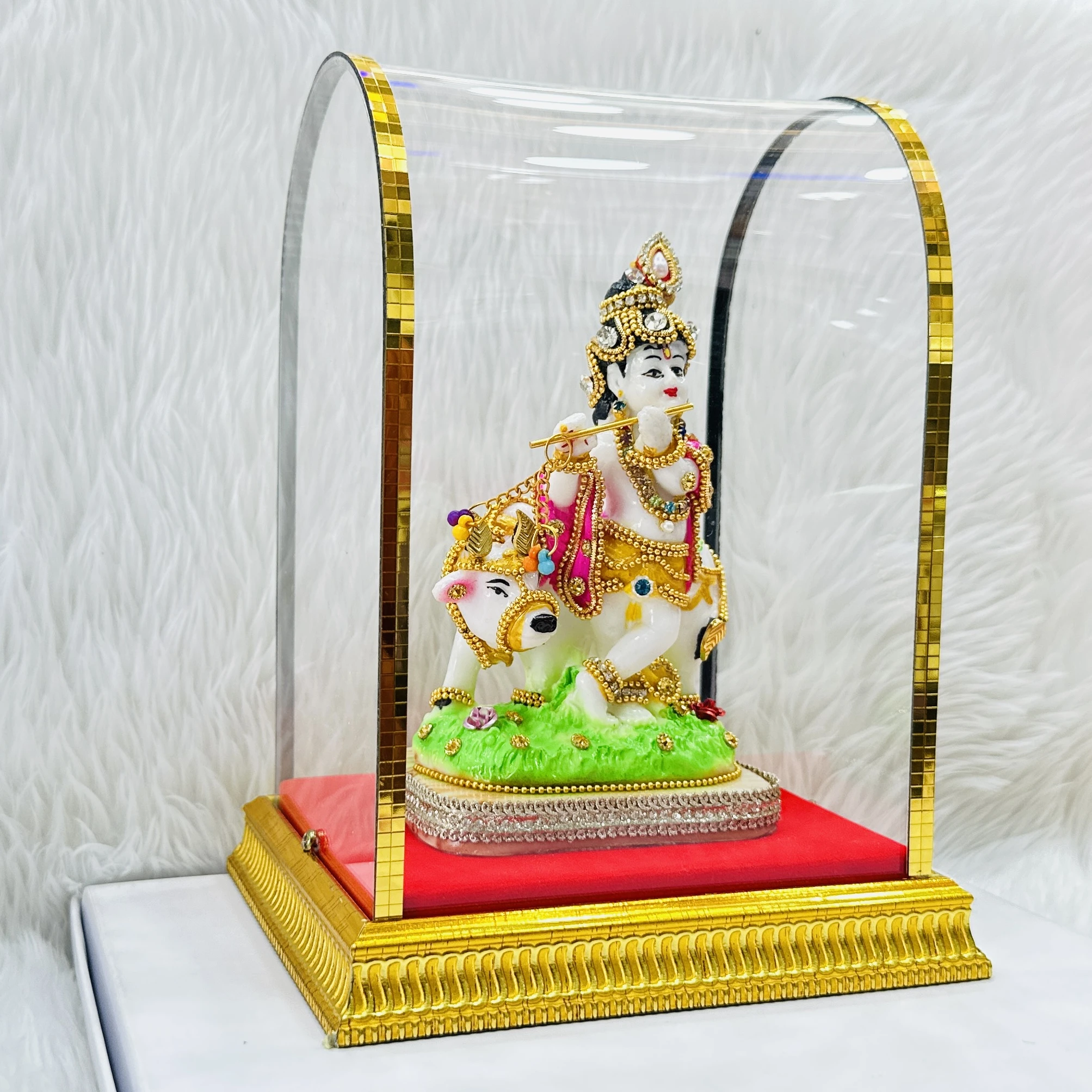 Lord Krishna and a cow housed within a protective glass case.