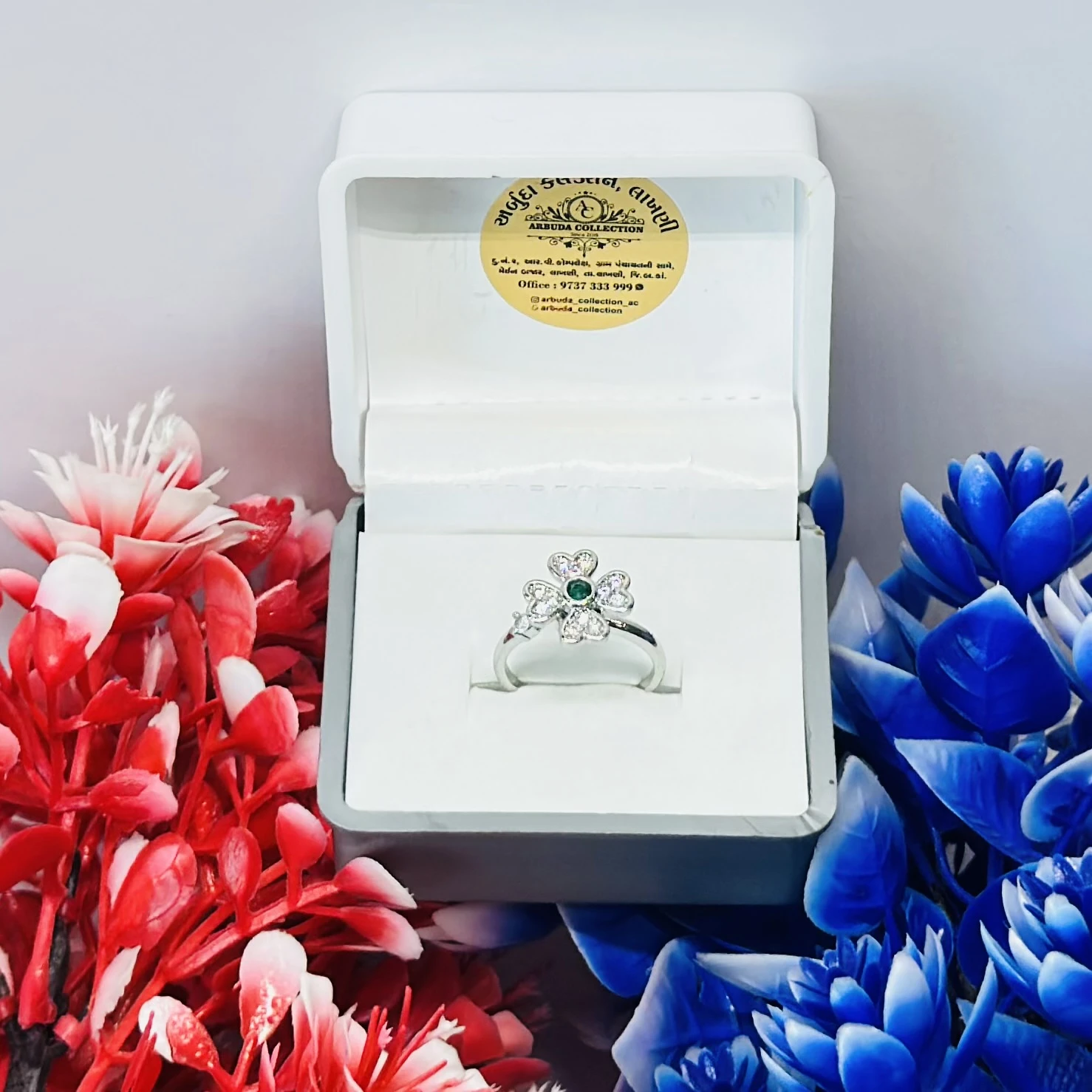 Silver flower toe ring with a green center and diamond details.