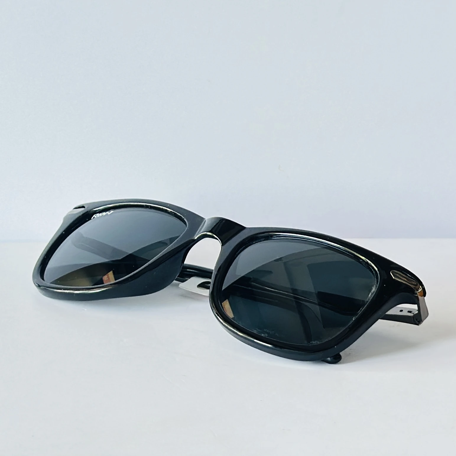 Black sunglasses appear to be similar to the iconic Ray-Ban Original Wayfarer.