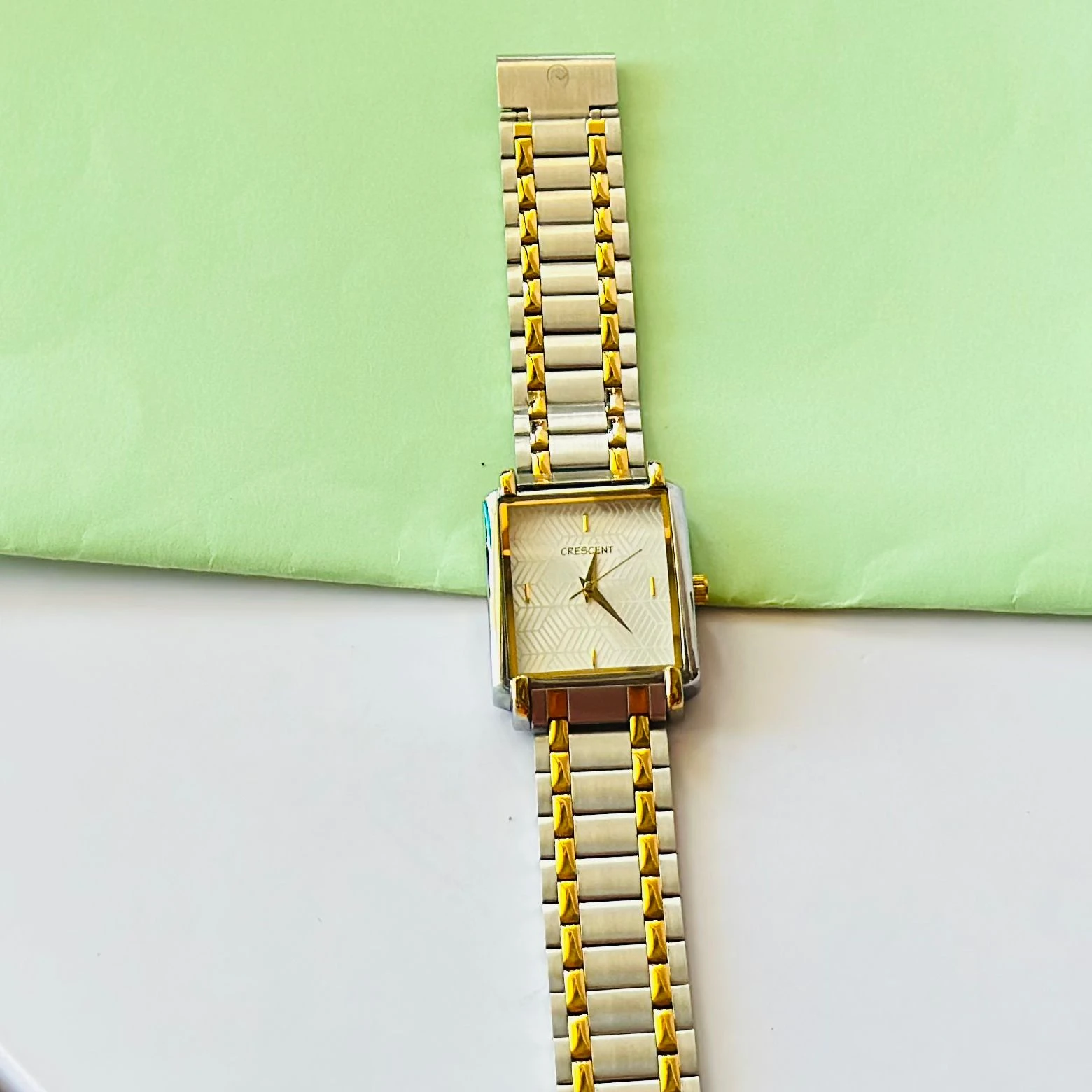Crescent analog watch with a rectangular case and a two-tone (silver and gold) metal bracelet.