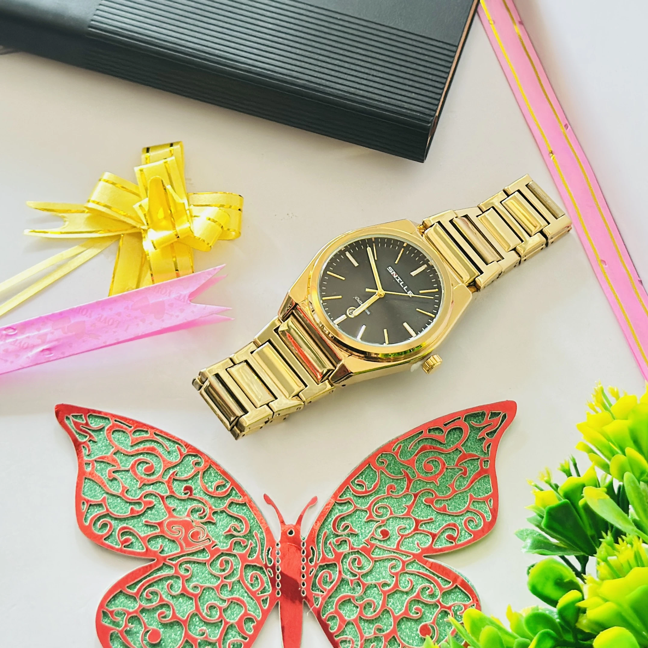 Snille brand gold-toned analog watch with a black dial and metal strap.
