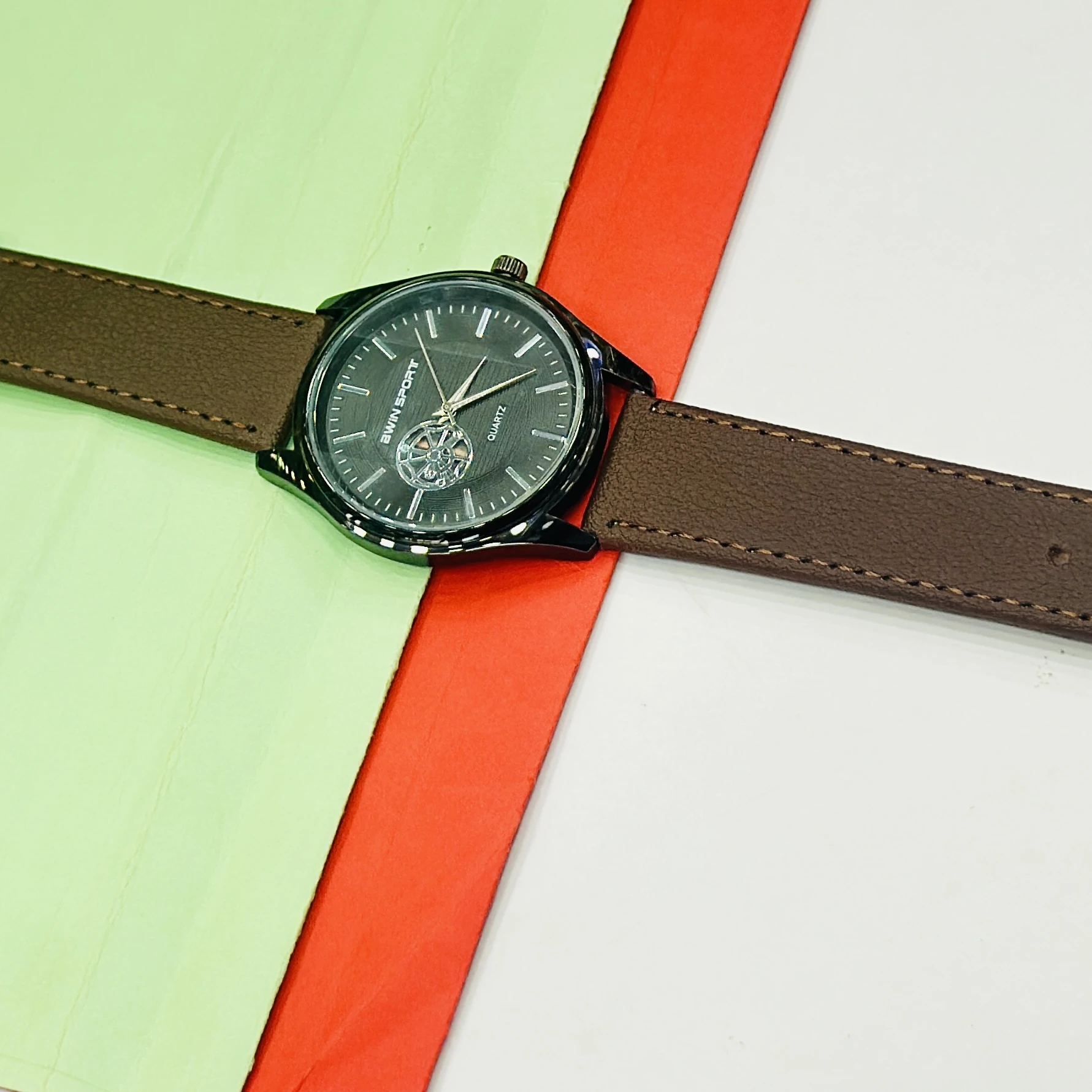 Quartz watch with a brown leather strap and a black dial.