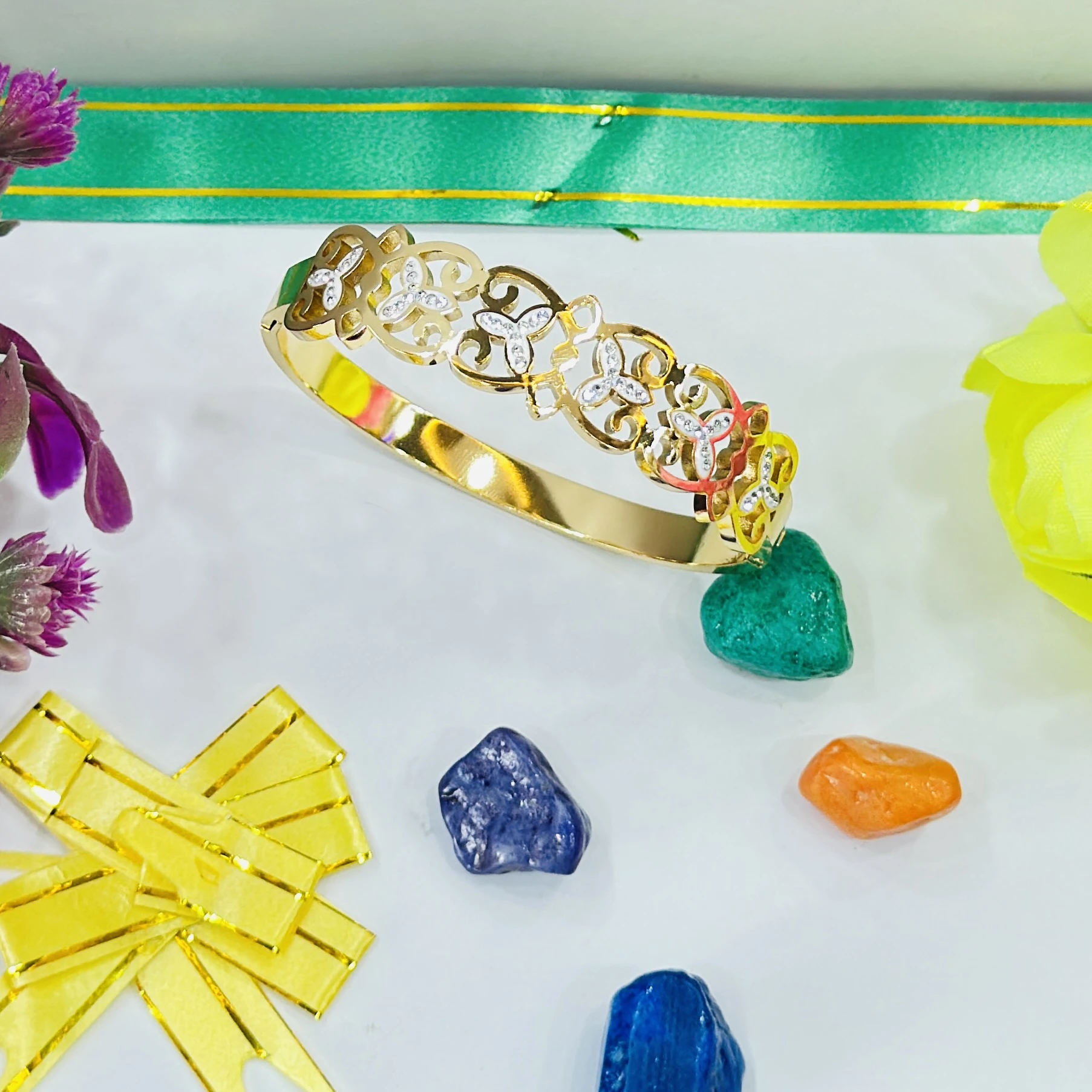 Gold plated bangle bracelet featuring floral motifs studded with cubic zirconia