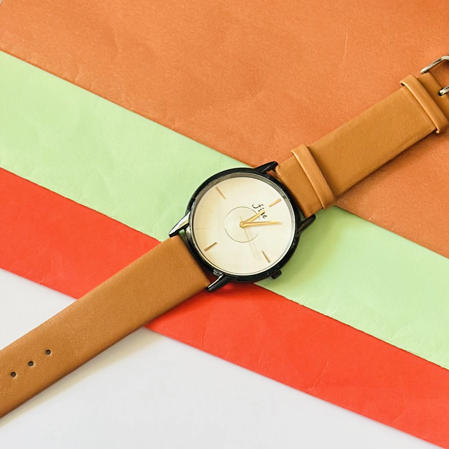 Analog wrist watch with a brown leather strap.