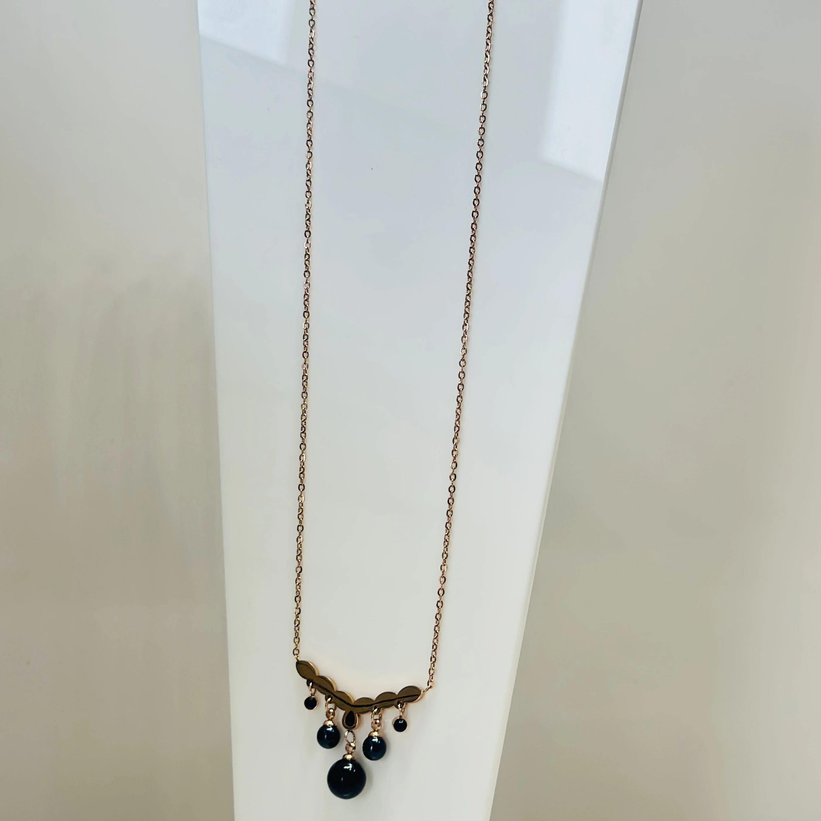 Rose gold-plated pendant necklace with a leaf-motif pendant and black beads.