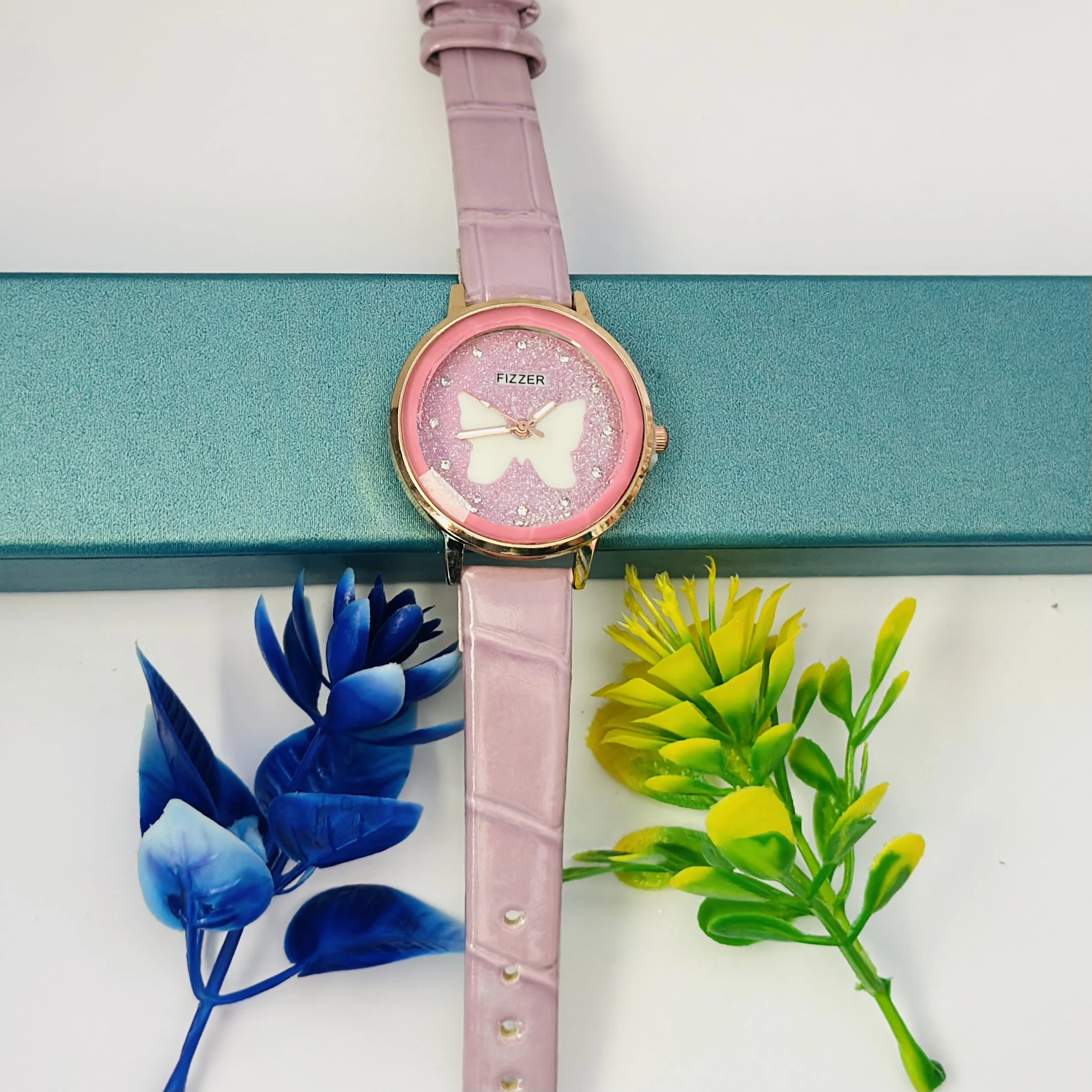 Pink analog watch with a butterfly design and a leather-style strap.
