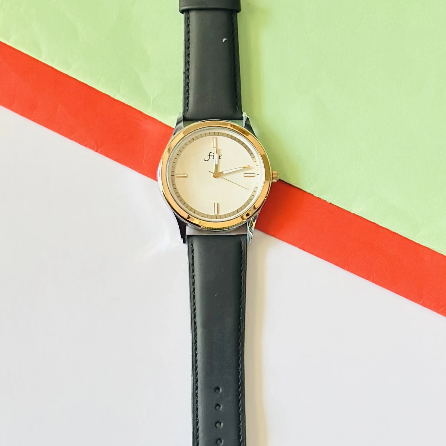 Analog wristwatch with a gold-tone case and a black leather strap.
