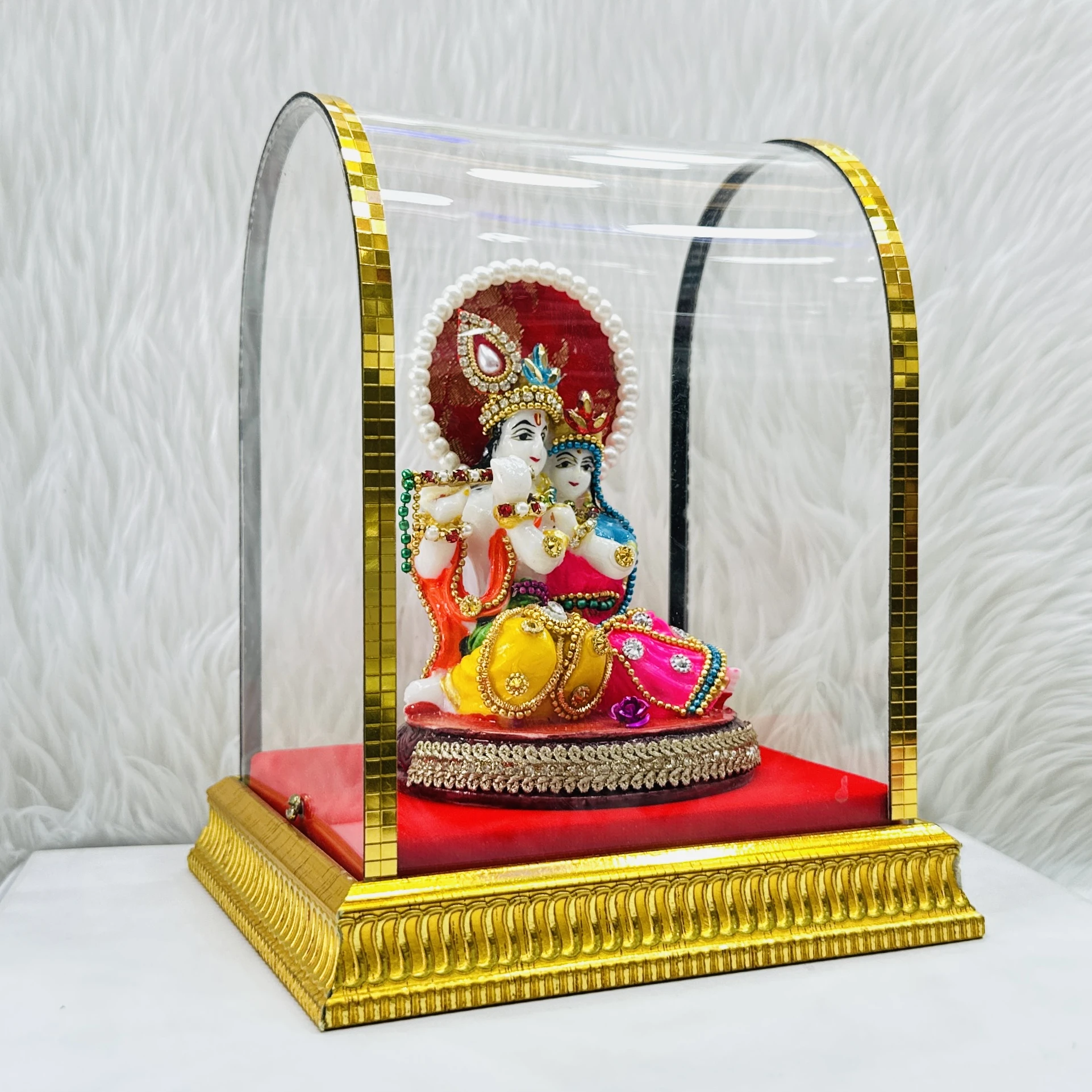 Radha Krishna statue enclosed in a protective glass case.