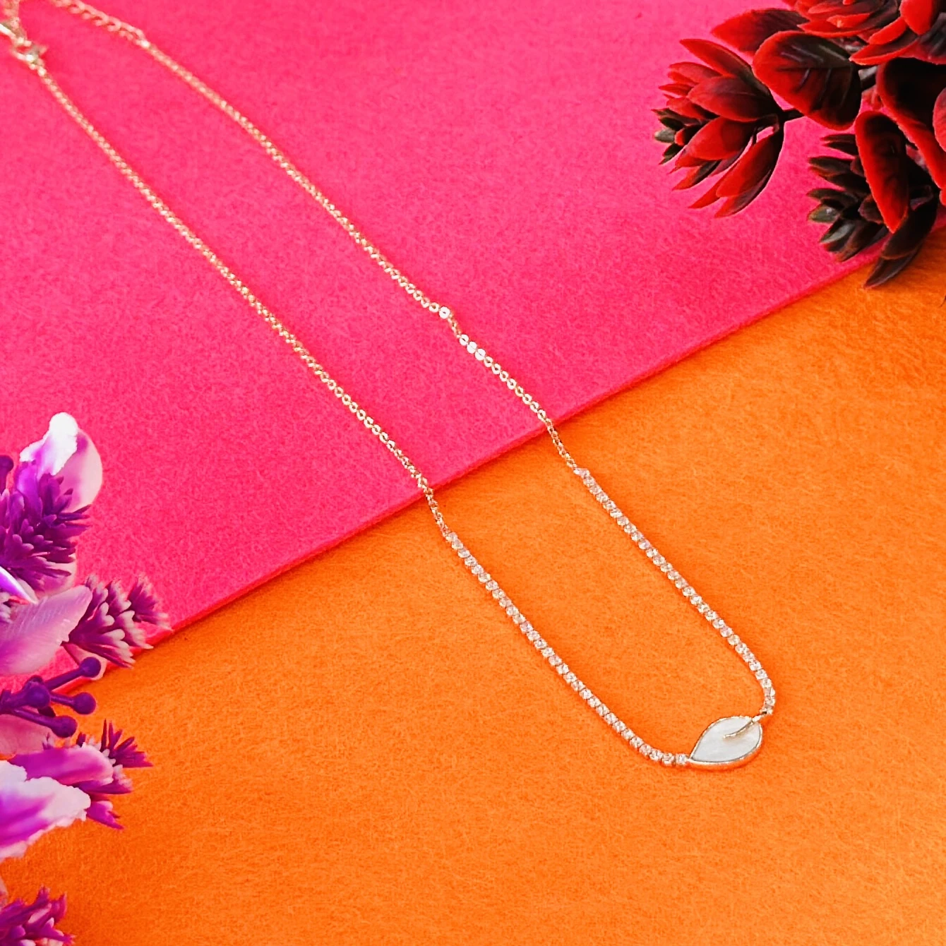 Gold plated chain necklace with a leaf-shaped white pendant.