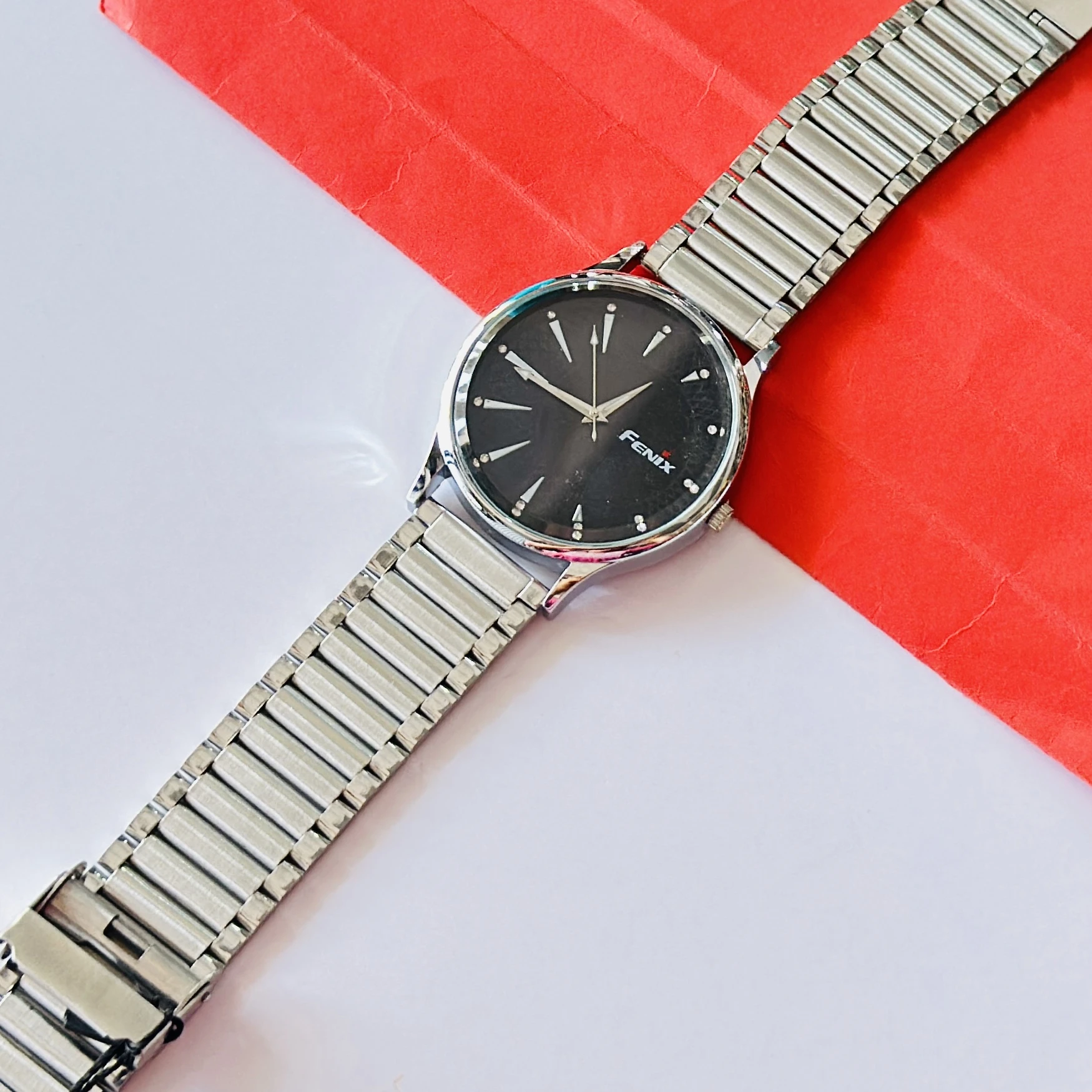 Analogue timepiece with a black dial and a silver stainless steel strap.