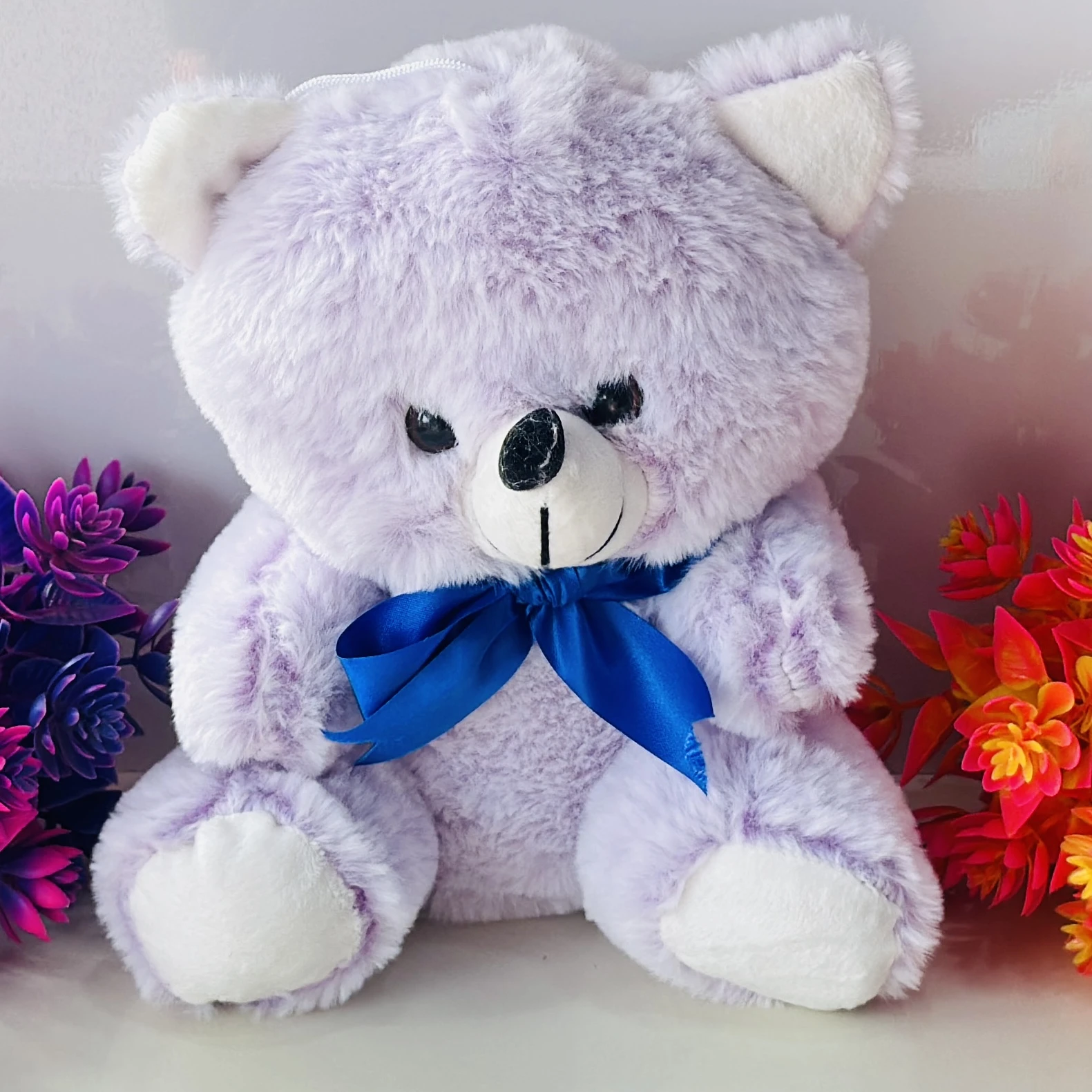 purple plush teddy bear with a blue ribbon