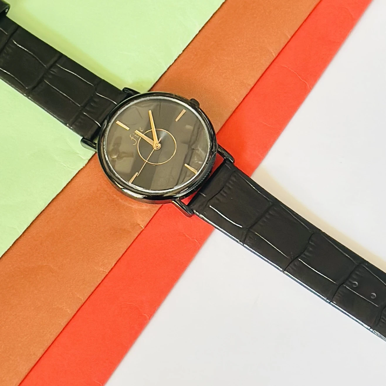 Black analog watch with a black textured leather-style strap.