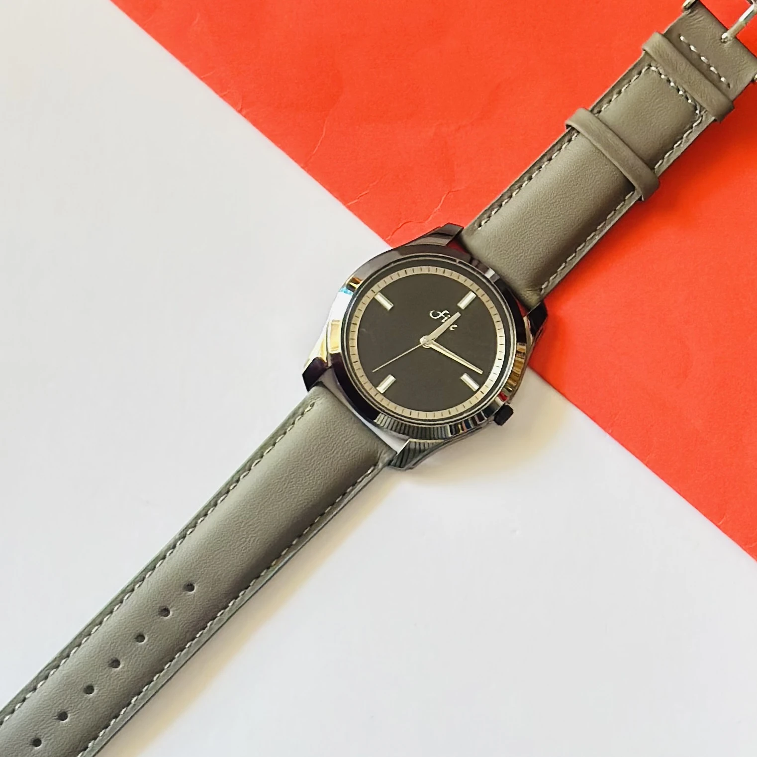 watch with a gray leather strap and a black dial.