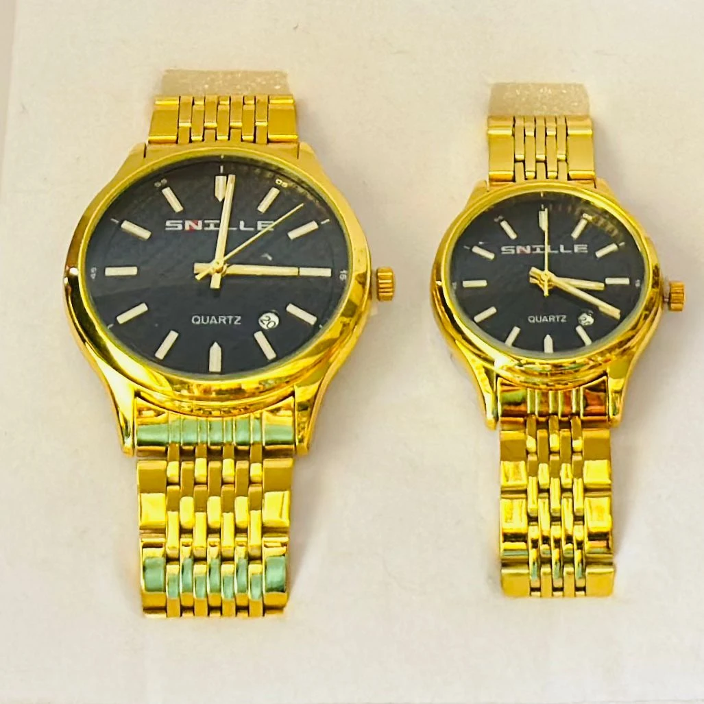 pair of Snille Date Series analog quartz watches for men and women with gold-tone link bracelets and black dials.