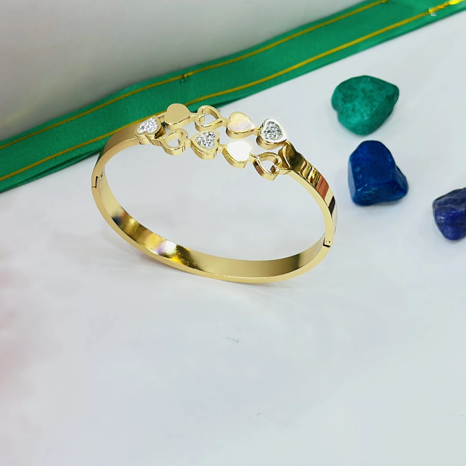 Glitzica enchanted hearts gold-plated kada bracelet with a hinge clasp.