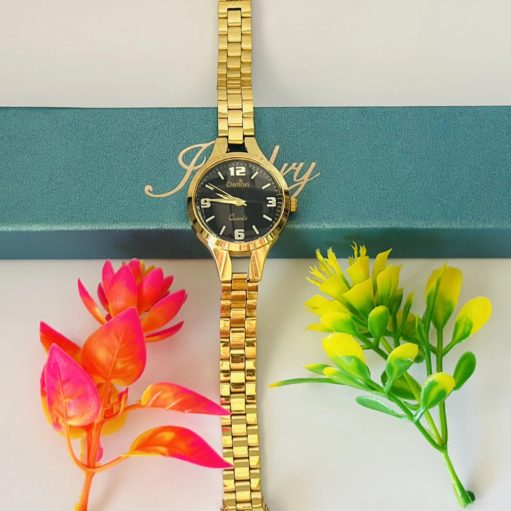 Analog quartz watch with a black dial and a gold-tone stainless steel strap.