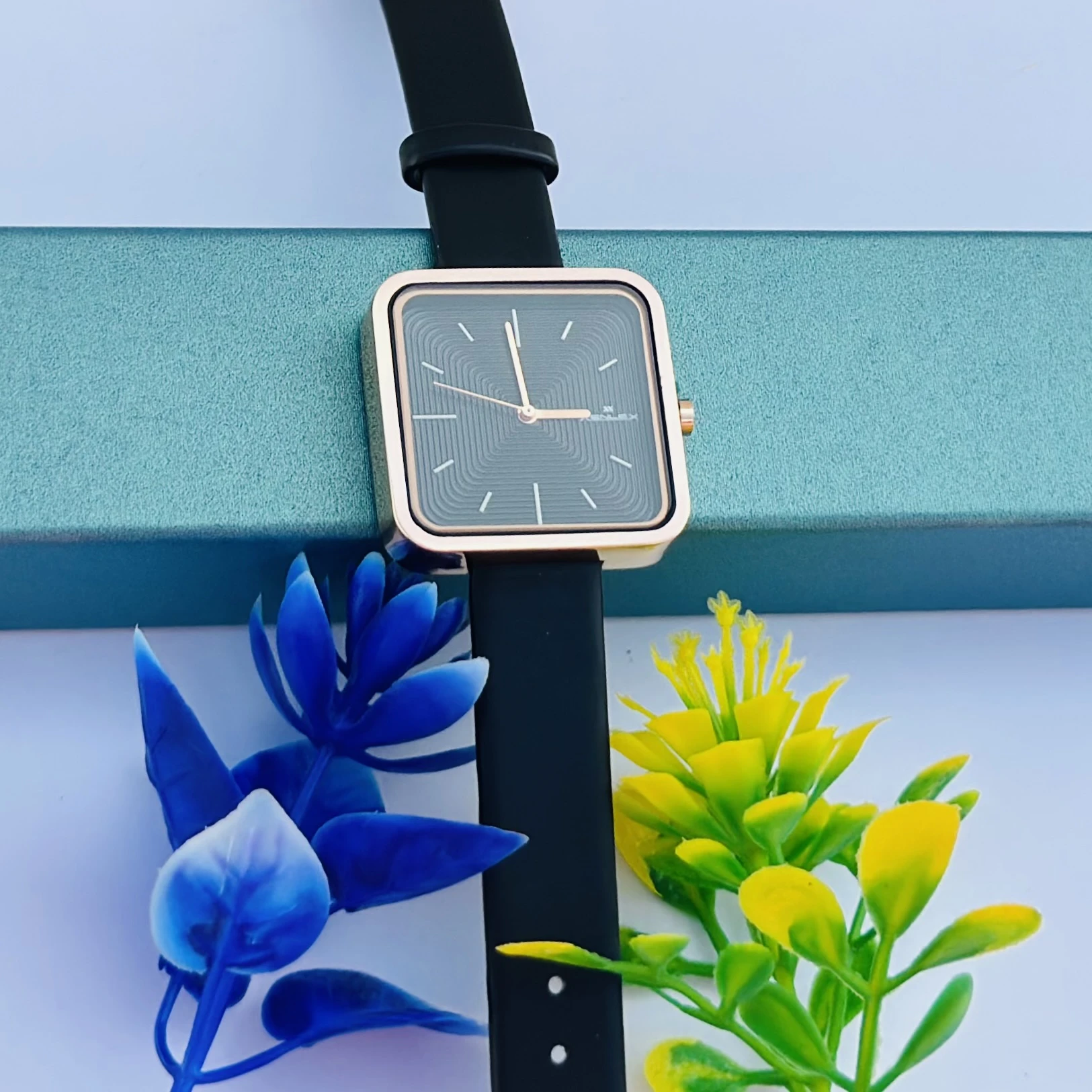 square-dial women's watch with a black strap and rose gold-tone case.