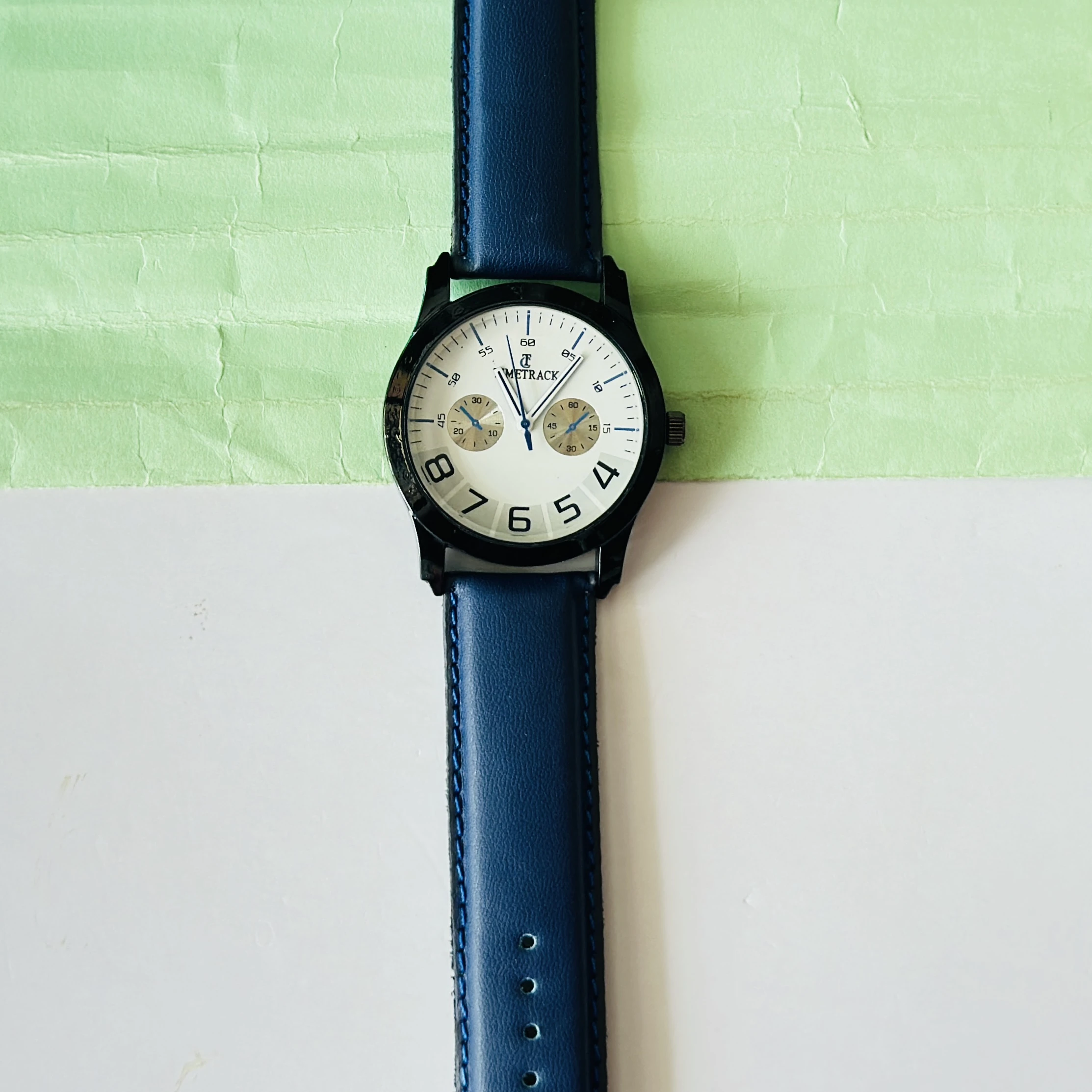 METRACK brand analog watch with a blue leather strap and a white dial