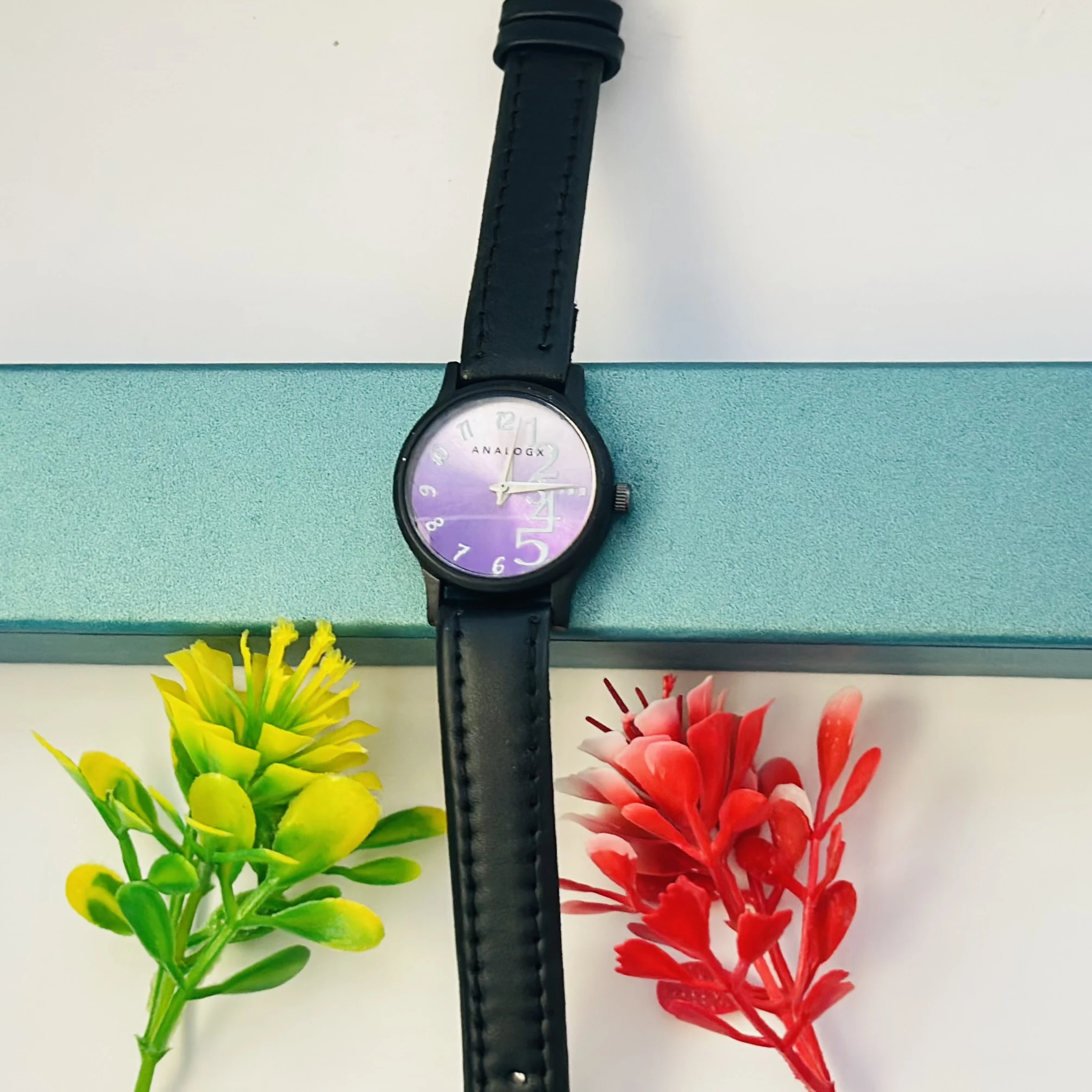 purple analog watch with a black leather strap.