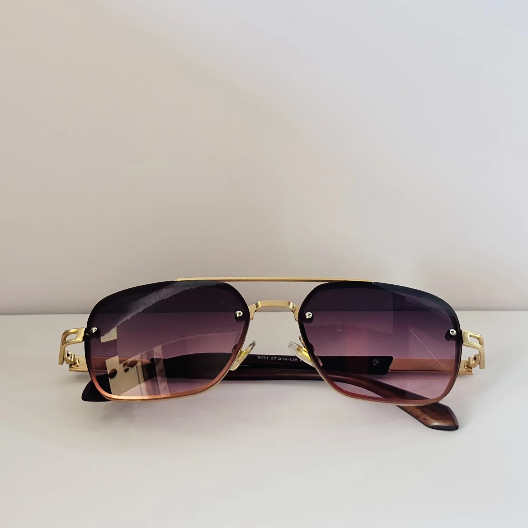 pair of gold-toned aviator sunglasses with gradient pink/purple lenses.