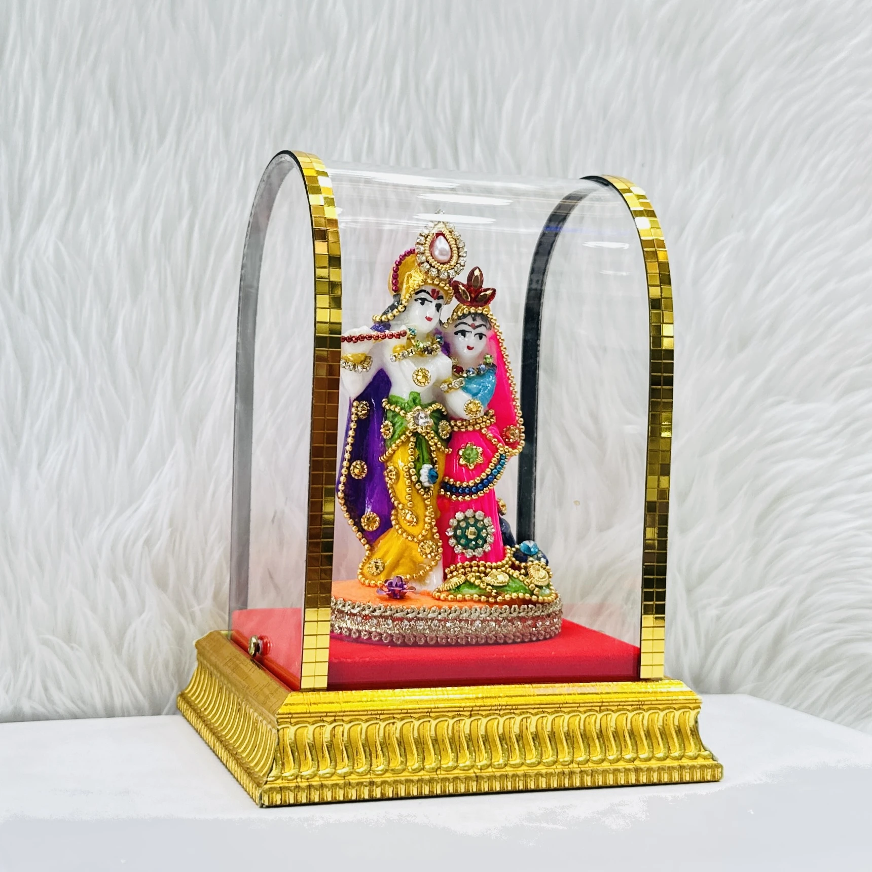 Radha Krishna statue enclosed in a protective glass case.