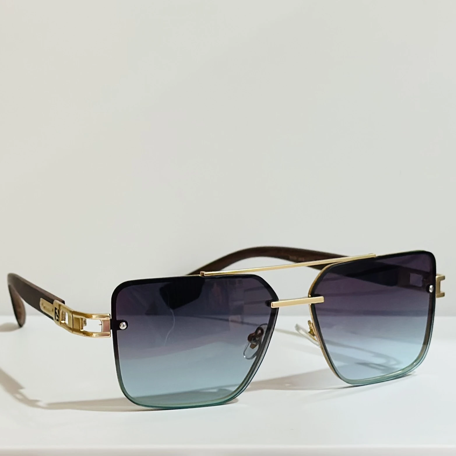 Pair of of aviator-style sunglasses with a gold-tone metal frame and blue gradient lenses.