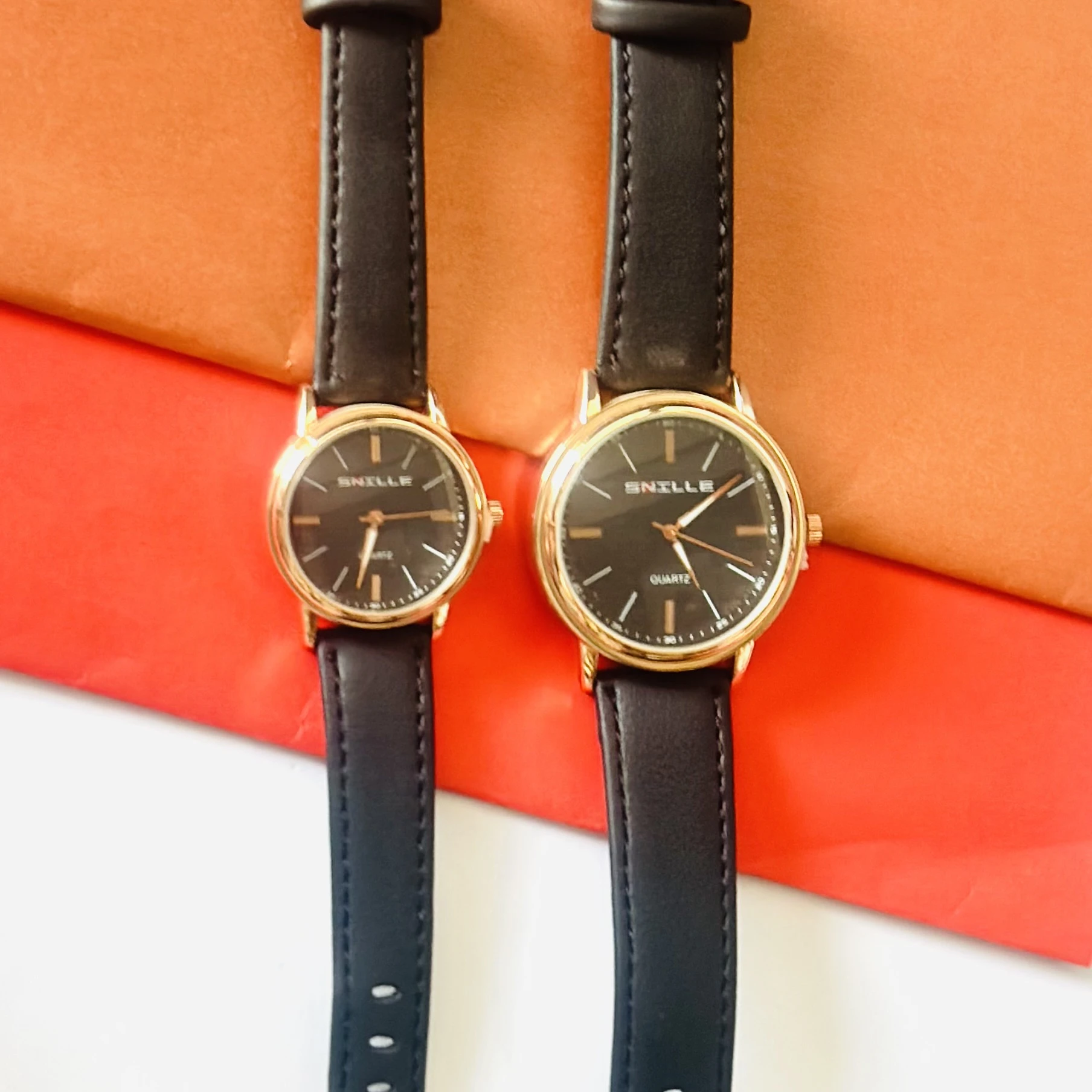 black "Snille" quartz watches with gold-tone cases and black faux leather straps