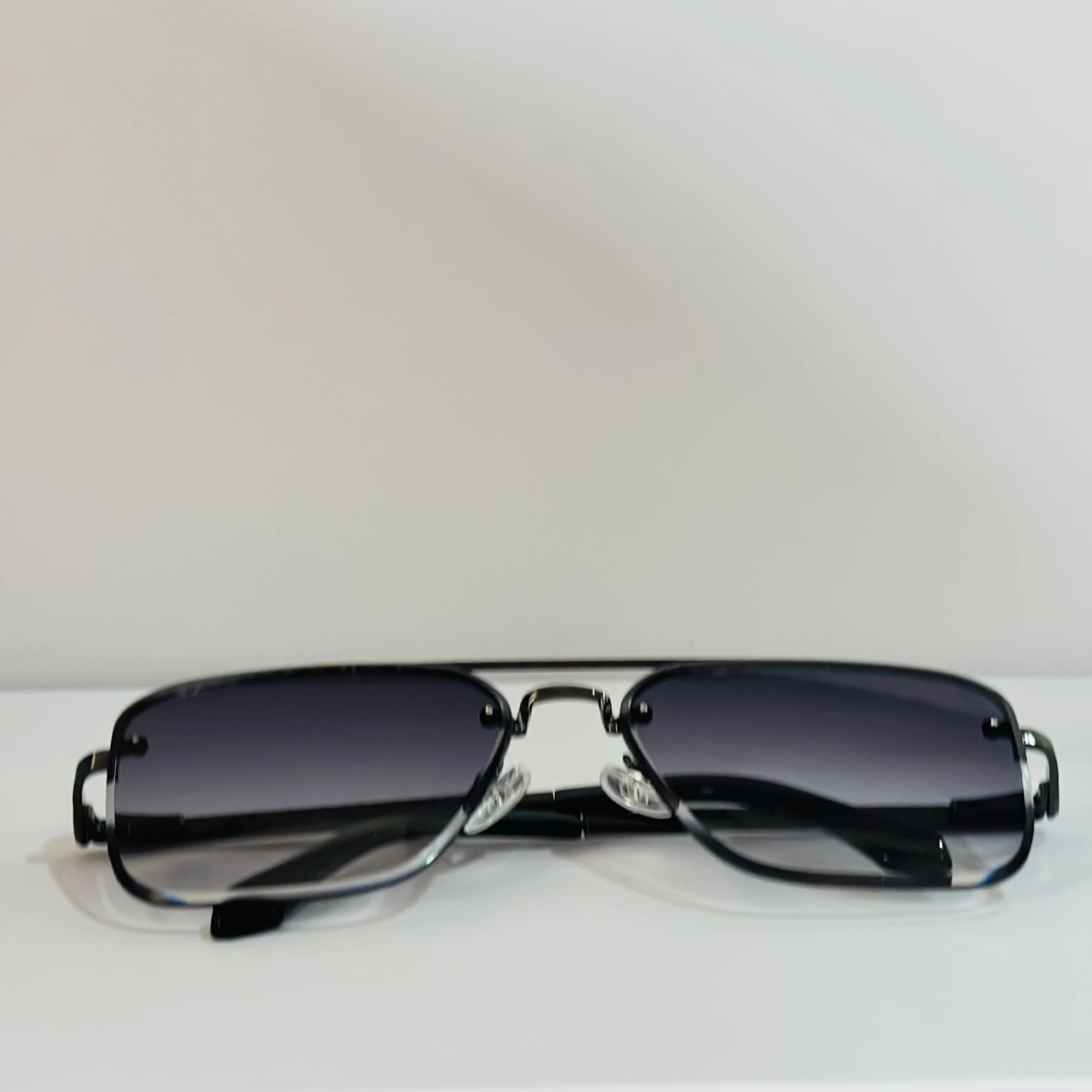 pair of aviator-style sunglasses with a black metal frame and grey gradient lenses.