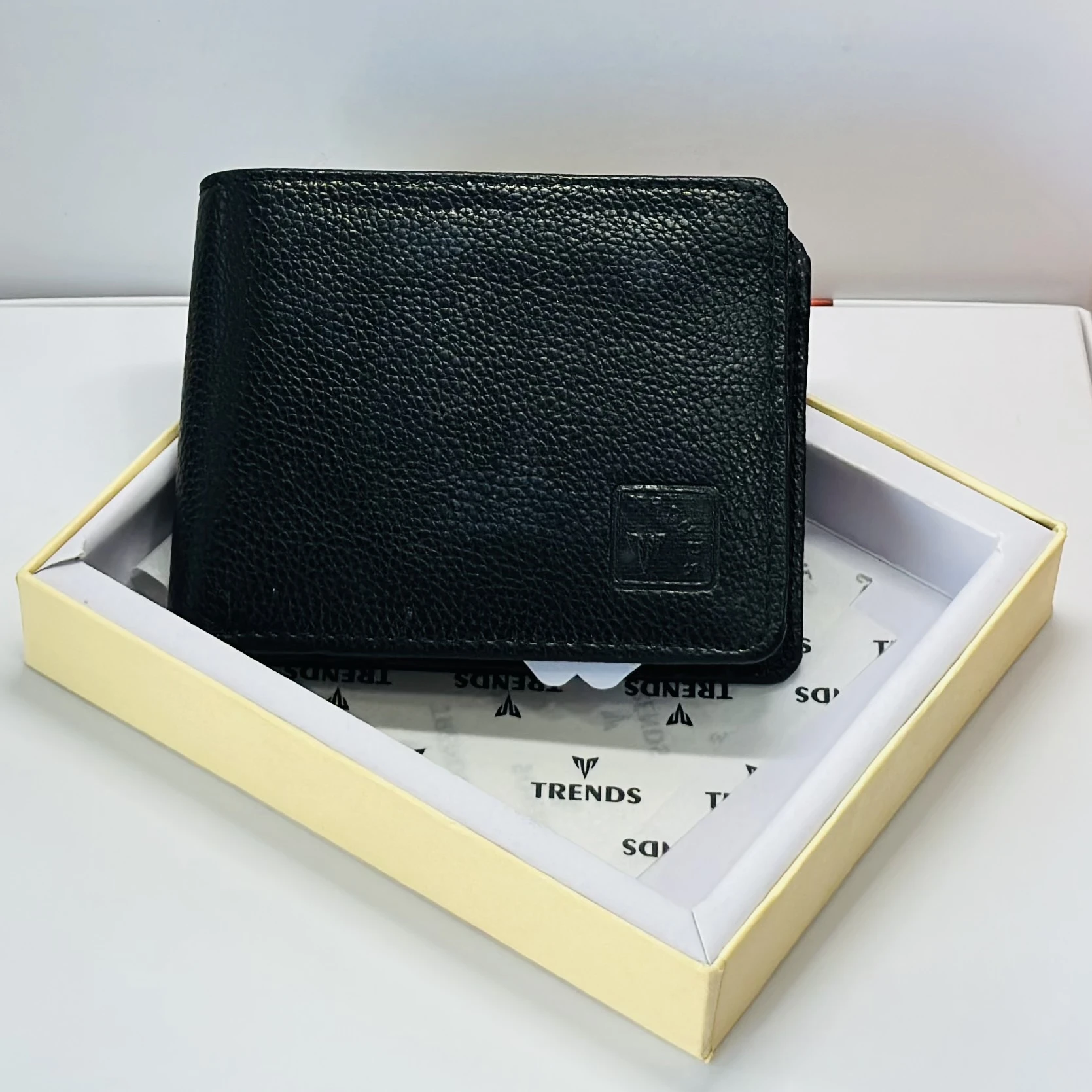Black leather bifold wallet with a "Trends" logo.