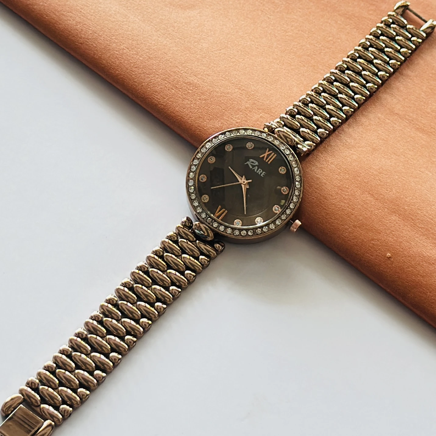 Rare analog watch with a bronze-toned metal bracelet and embellished dial.