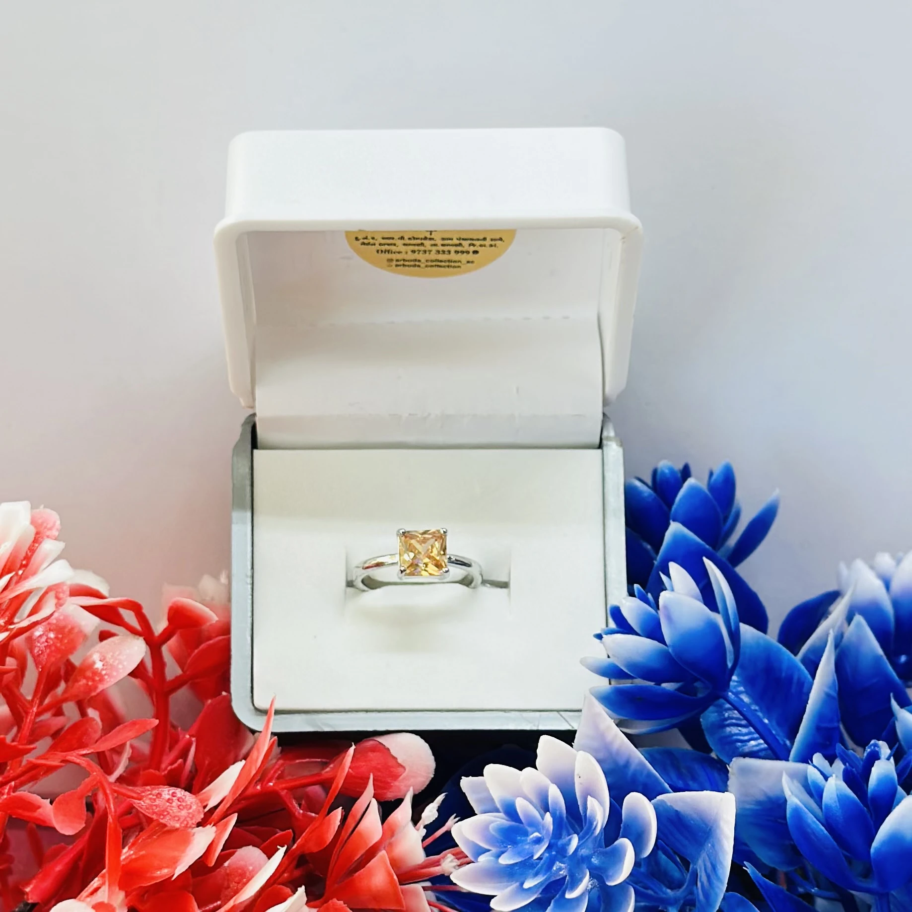 silver-toned solitaire ring with a square-cut yellow gemstone, possibly a citrine or cubic zirconia.
