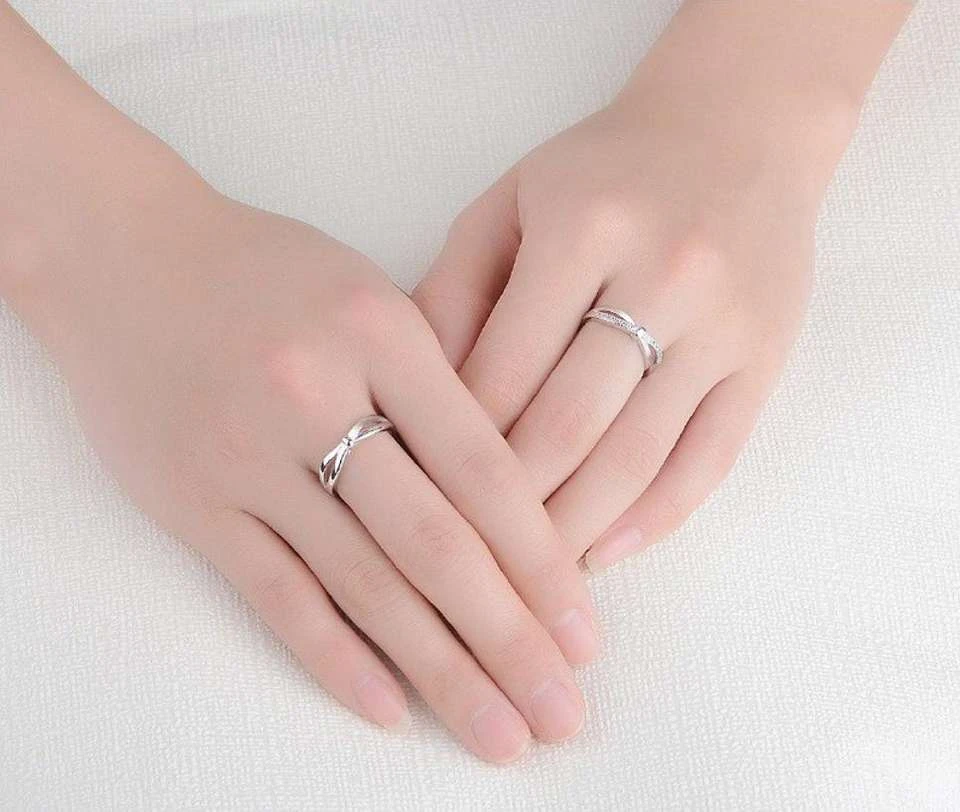 set of silver-plated, adjustable couple rings featuring a double bowknot design, with one ring studded with cubic zirconia stones.