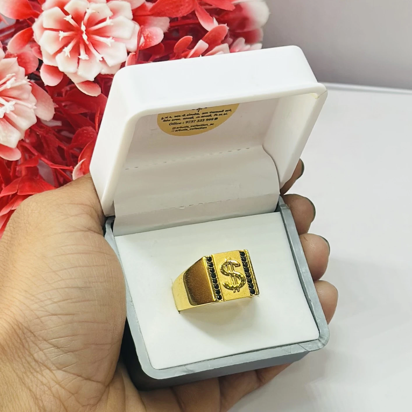 Gold toned men's ring featuring a dollar sign emblem and black accents.