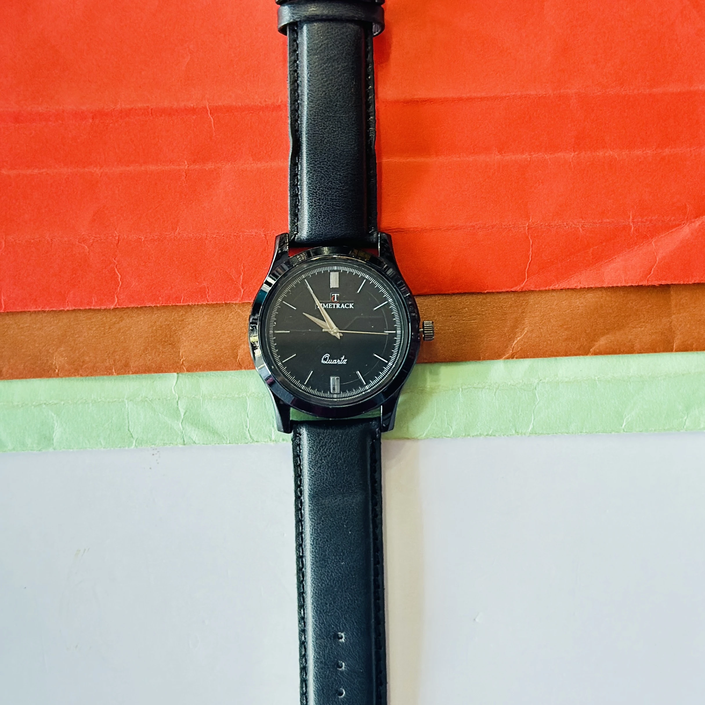 Timetrack Quartz wristwatch features a black analog dial and a black leather strap.