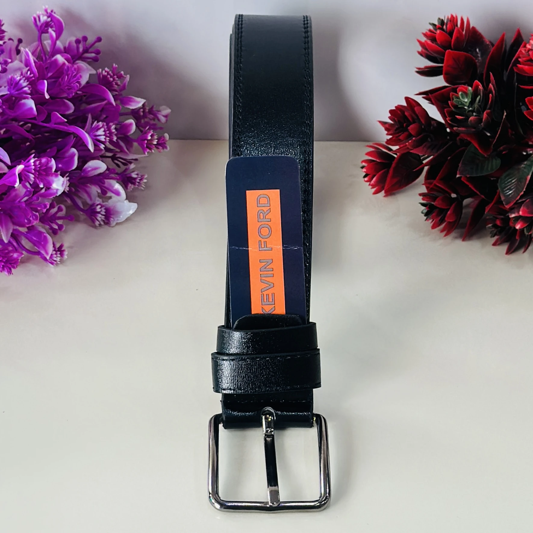 black belt with a silver-tone buckle and a "KEVIN FORD" label.