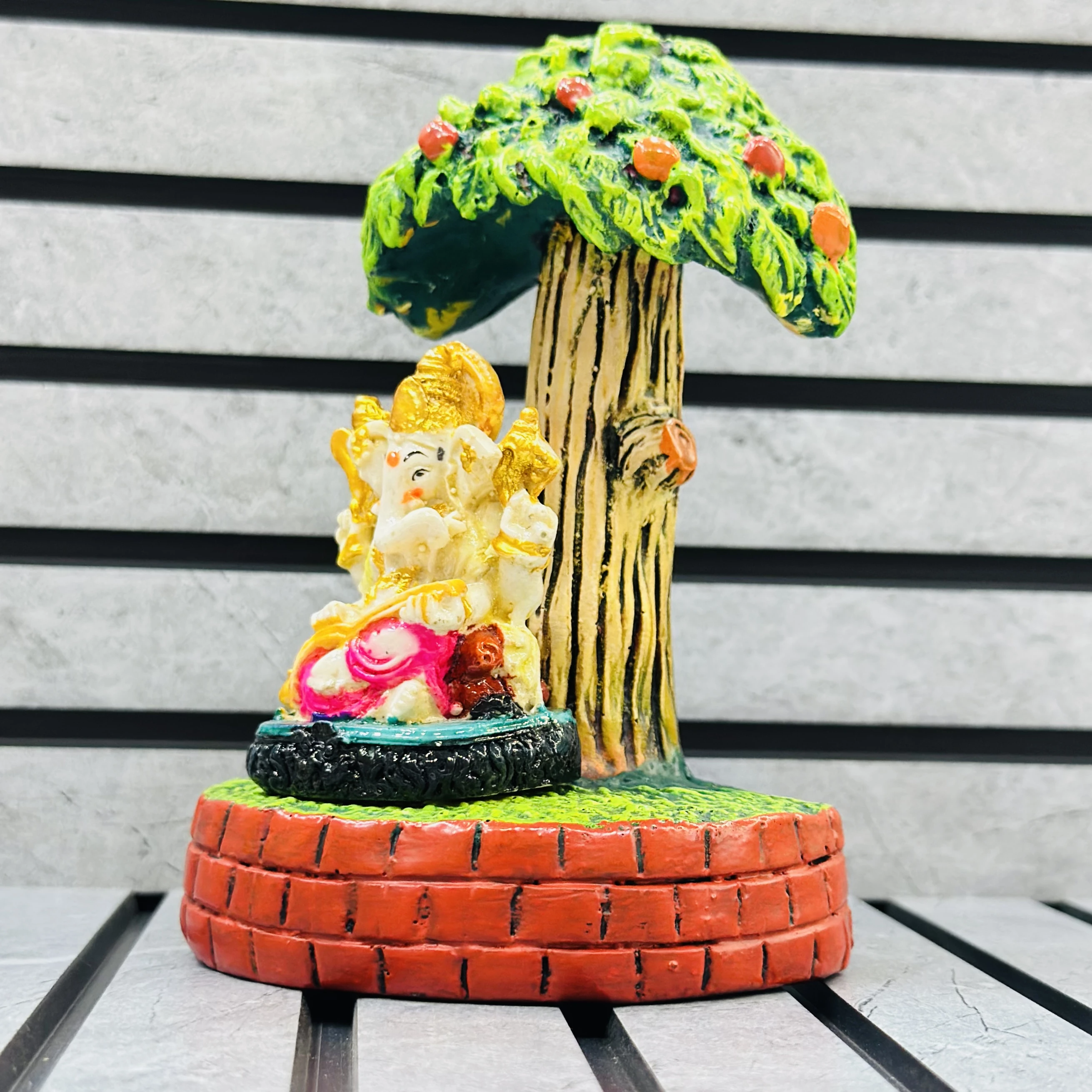 small statue of the Hindu deity Lord Ganesha seated under a tree