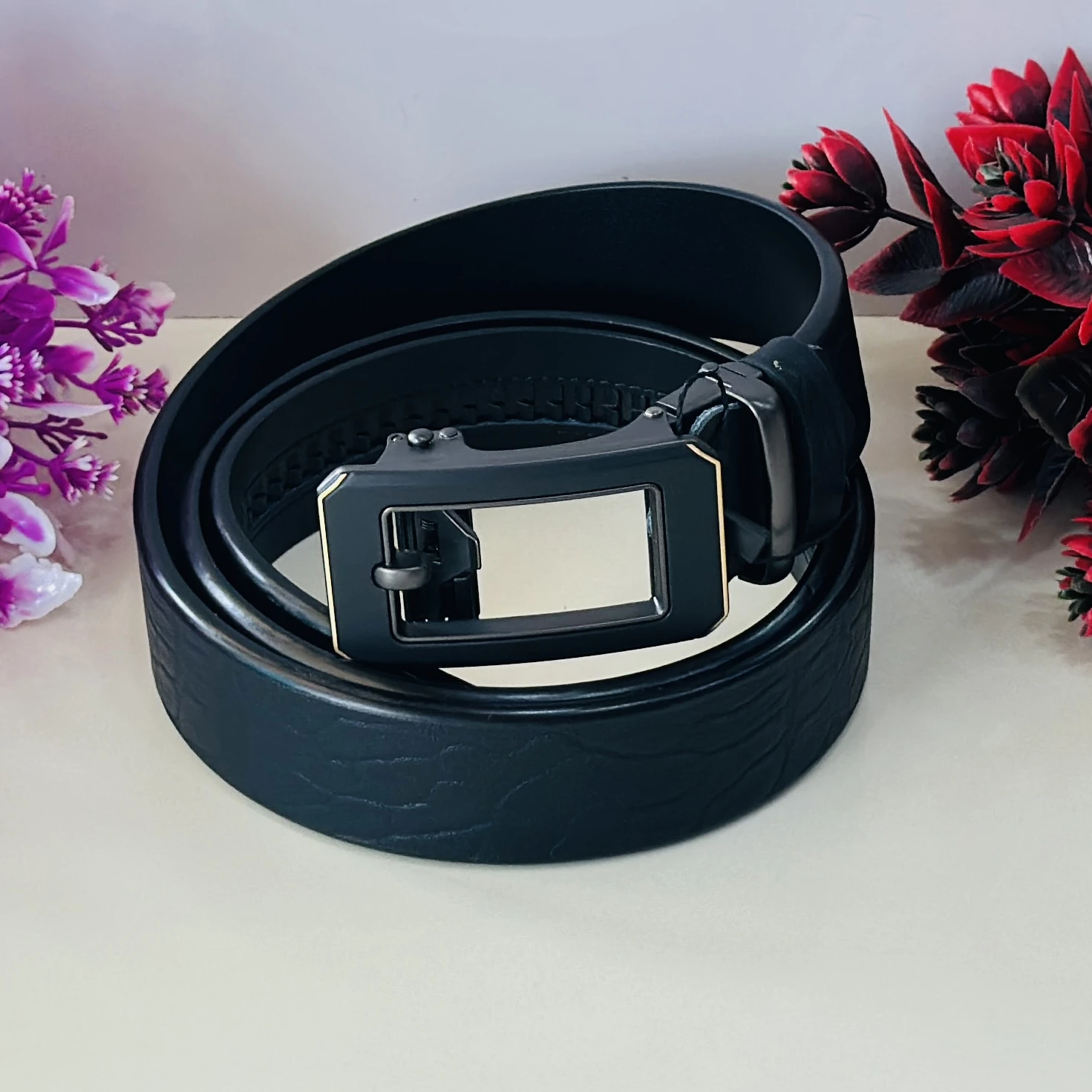 Black leather belt with a metal plaque buckle.