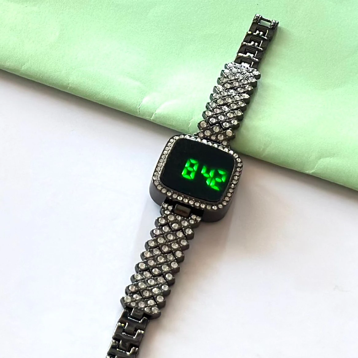 black-toned digital watch with an embellished rhinestone bracelet strap.