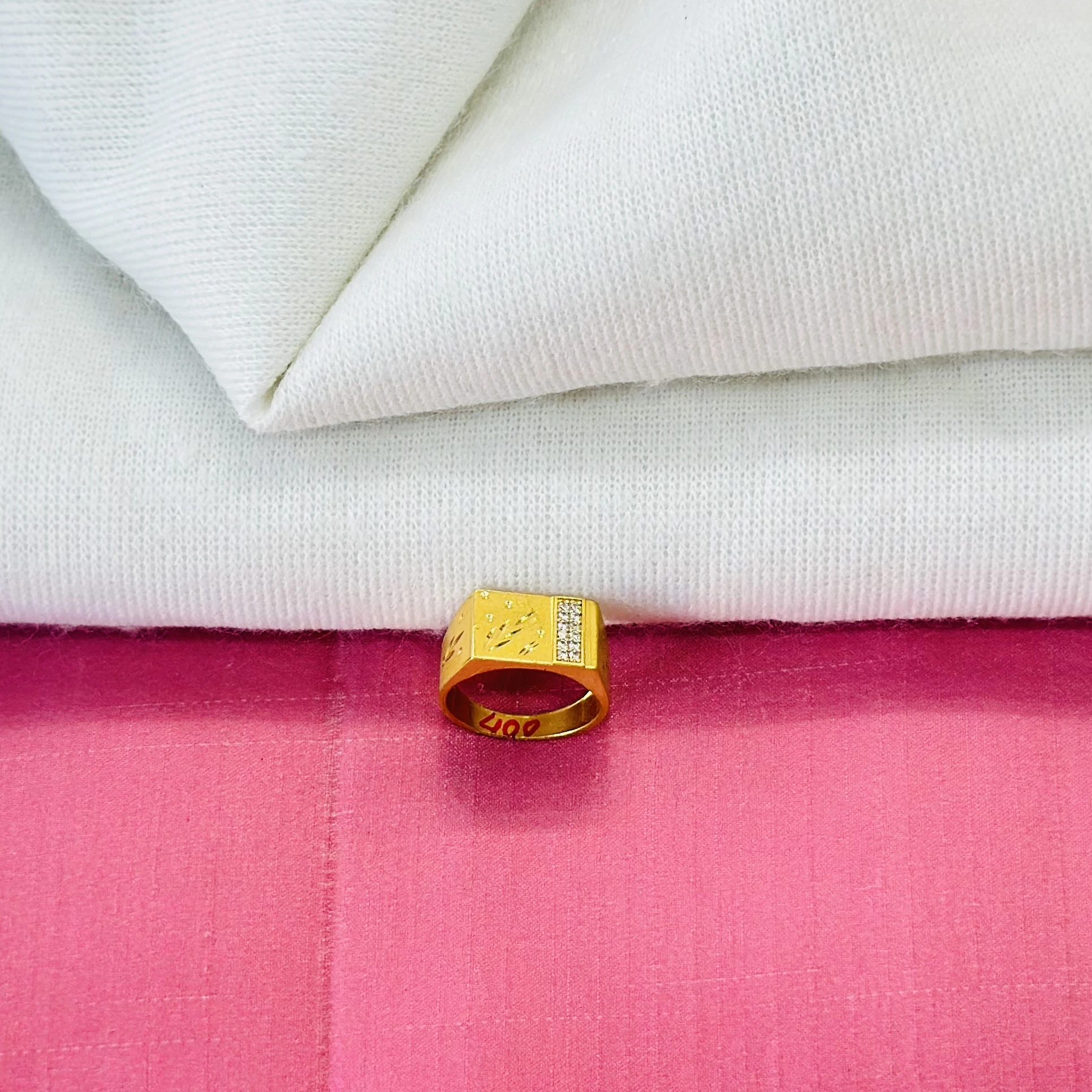 An engraved gold-toned men's ring with small white stones.