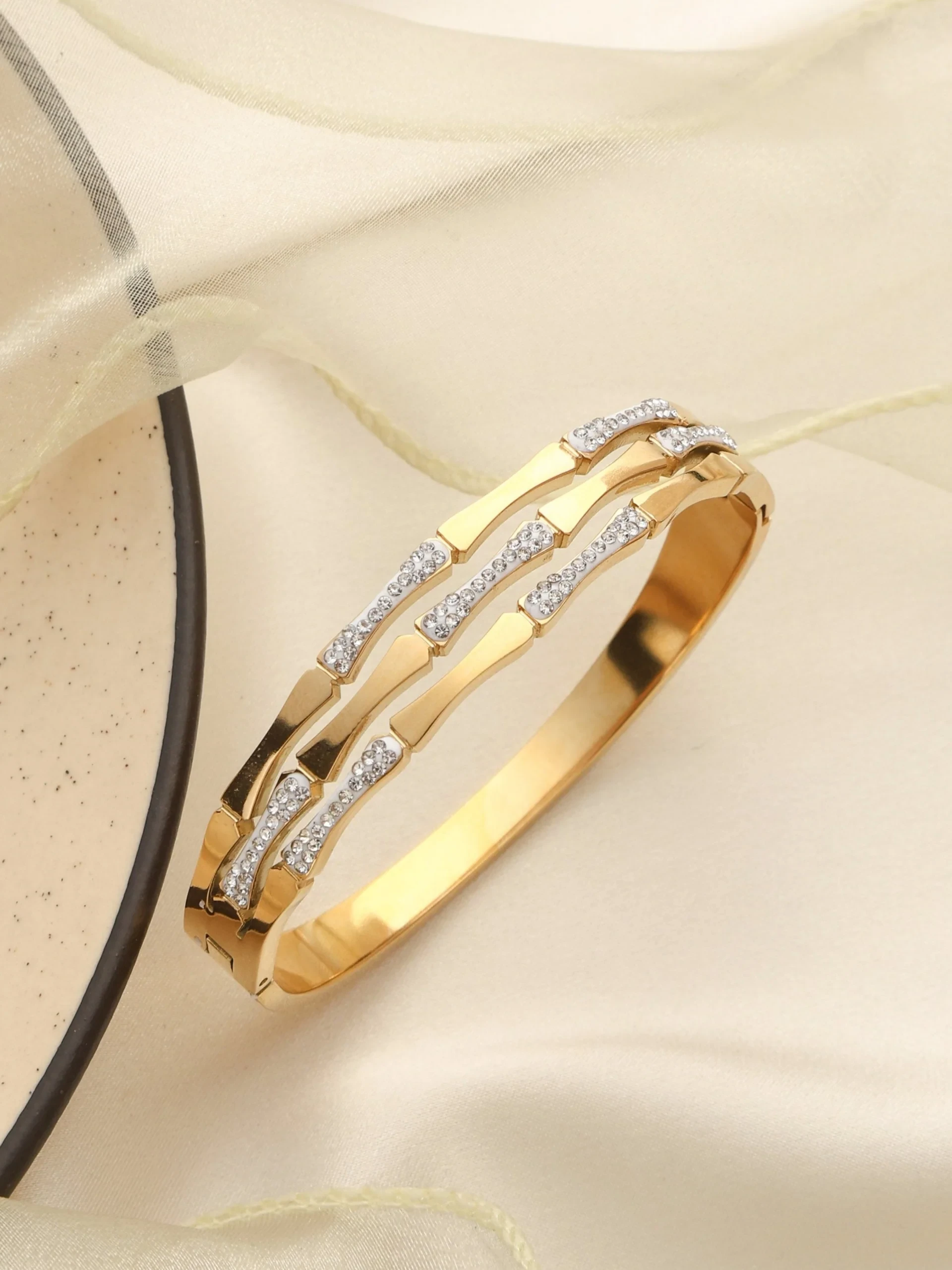 Gold plated bangle bracelet styled with clear rhinestones.