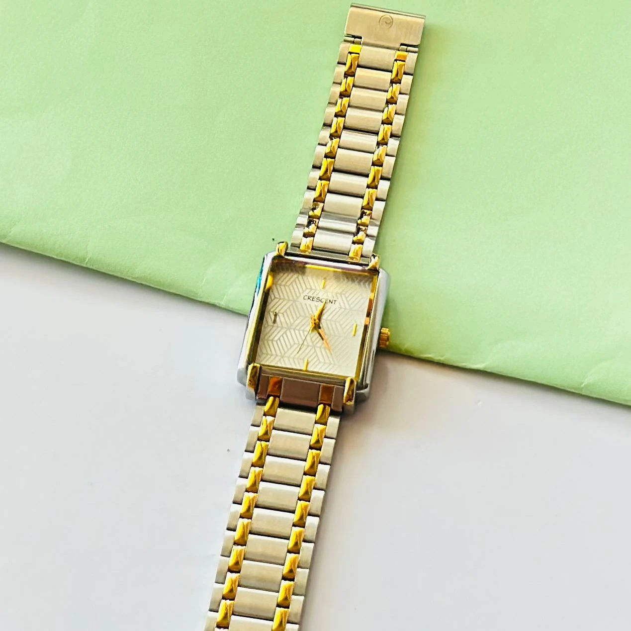 Crescent analog watch with a rectangular case and a two-tone (silver and gold) metal bracelet.