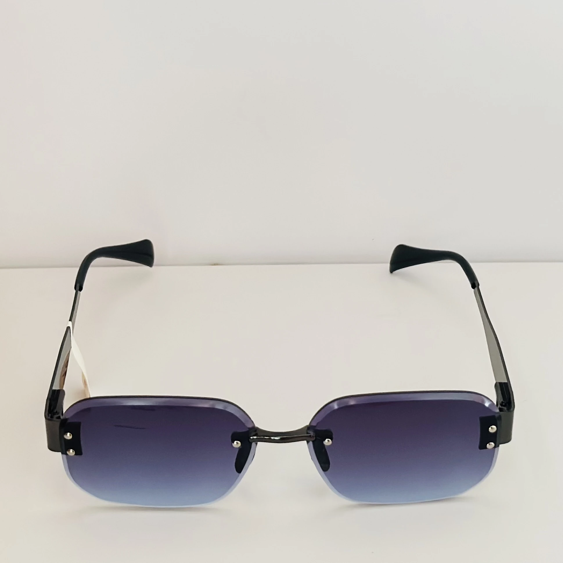 Frameless cut-edge sunglasses with black temples and a gradient tint.