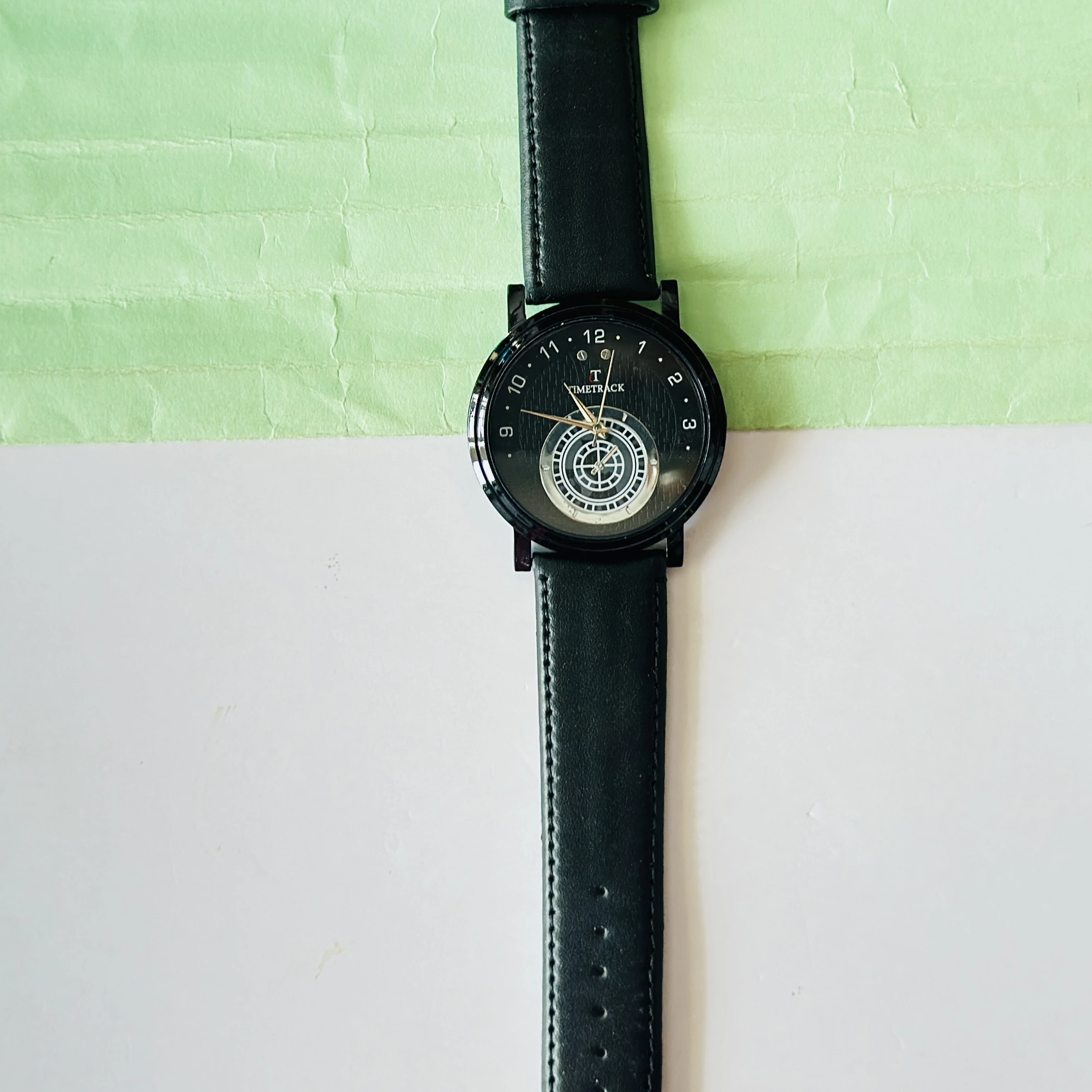 Timetrack quartz analog watch with a black leather strap and a distinctive patterned dial