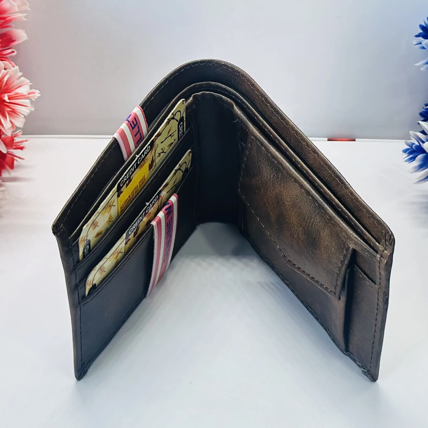 brown bifold wallet with "Genuine Wallet" text and a small "Queen" logo.